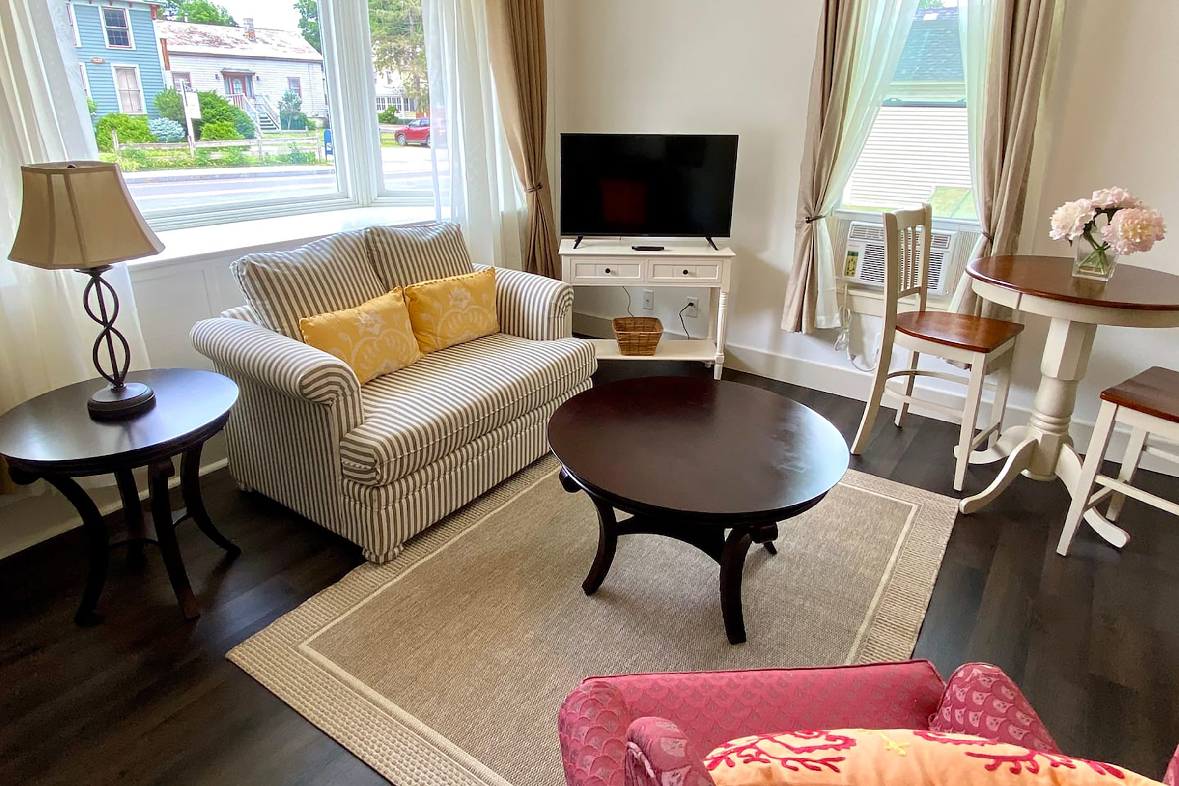 A living room with a pinstriped loveseat, coffee table, and television. 