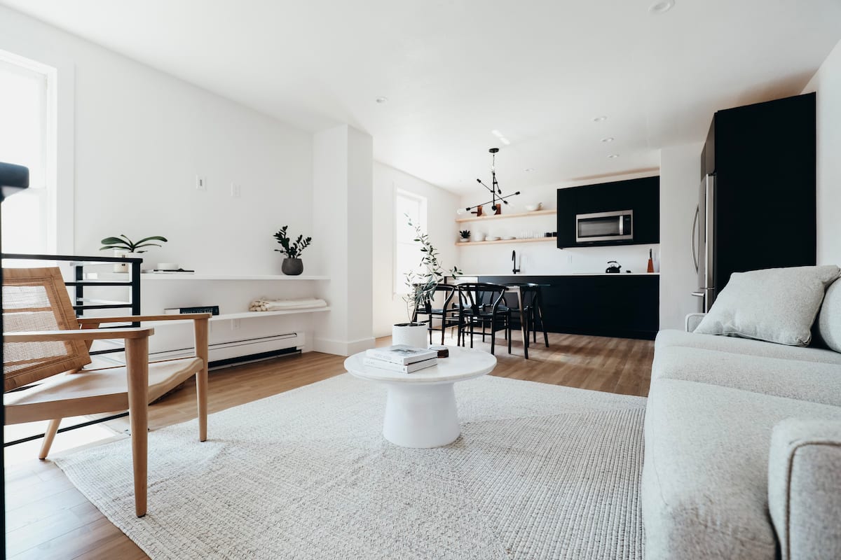 A mid-century modern living room with a tan lounge chair, white round coffee table, and white couch.