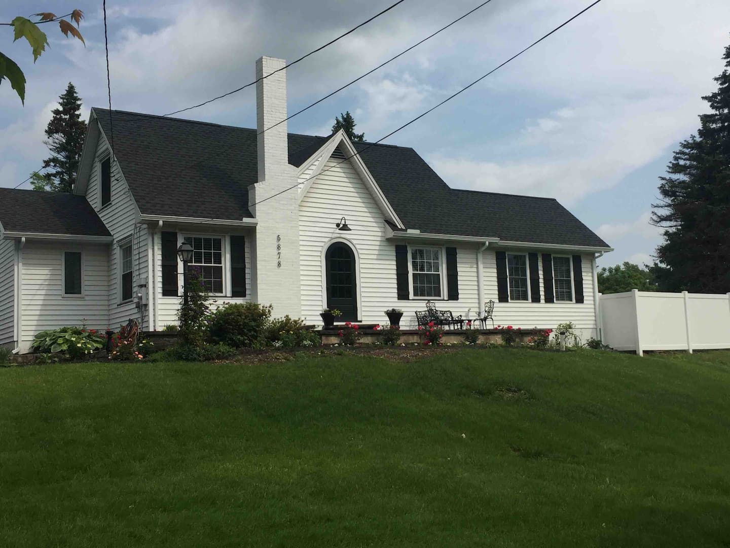 A white home with dark colored shutters and a large green front yard. 