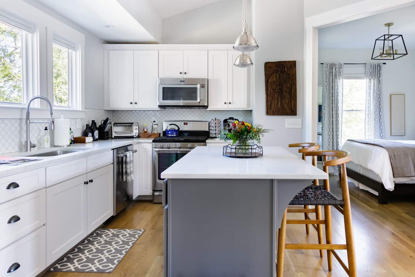 A contemporary kitchen with white countertops and tan dining seats