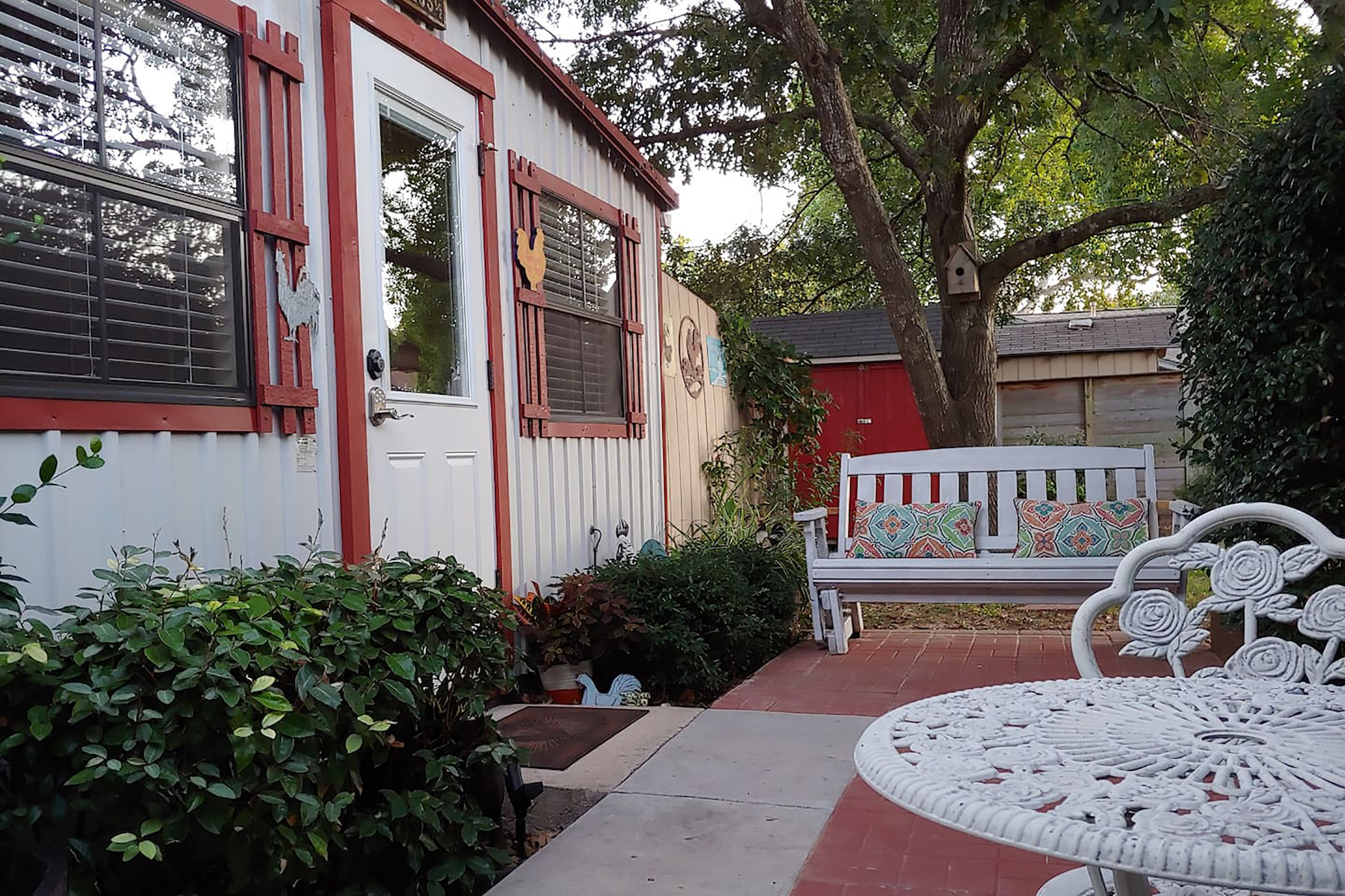 The entrance to white home with red siding and artwork of chickens hung along the entrance