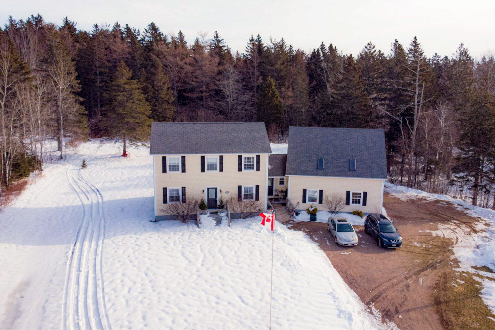 Ariel view of yellow home with Canadian flag waving from a flagpole in the front yard