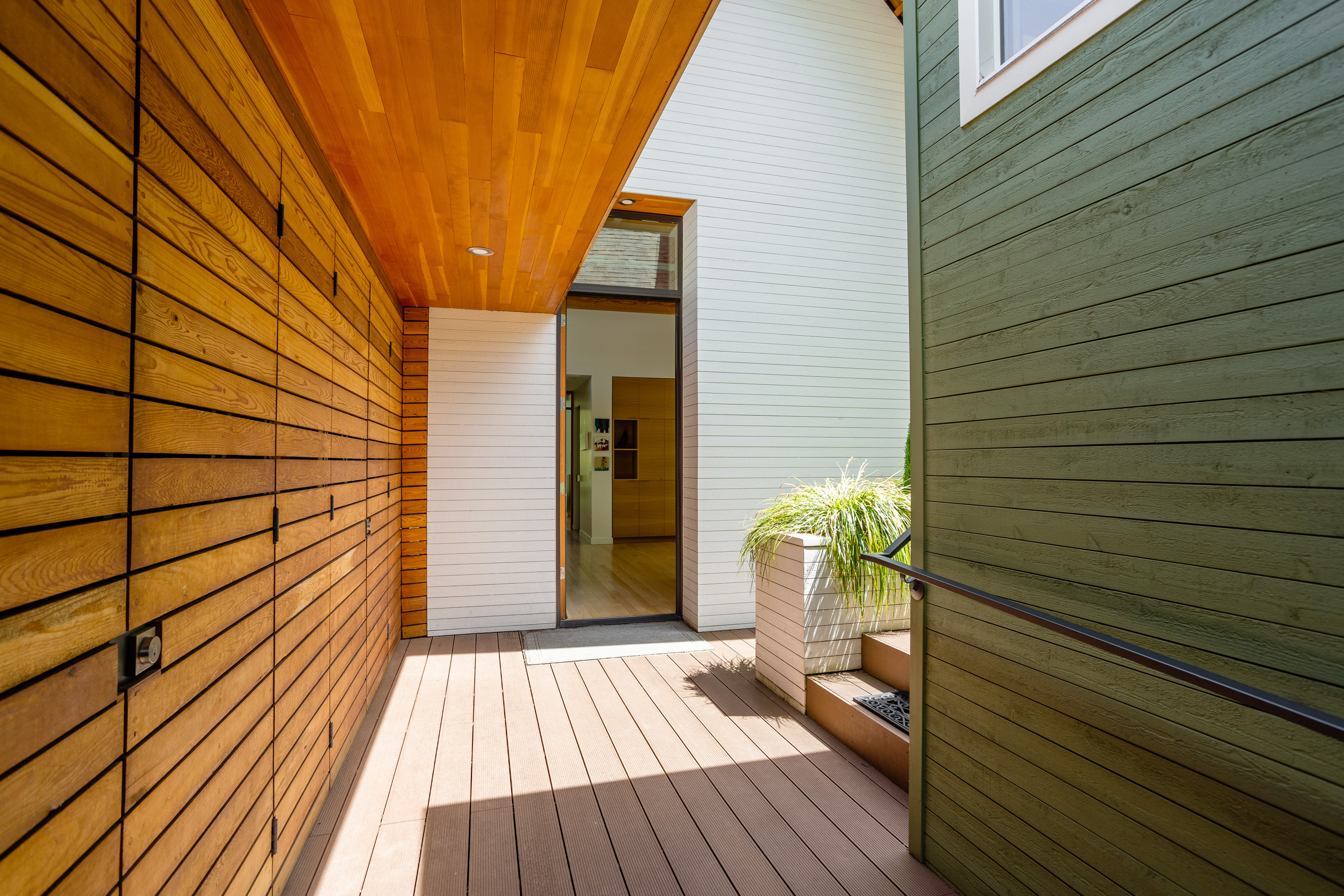 An outdoor step-free hallway leading towards a doorway entry to a home.
