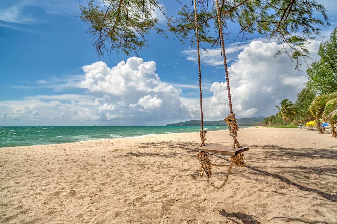 View of a beach with white sand and palm trees
