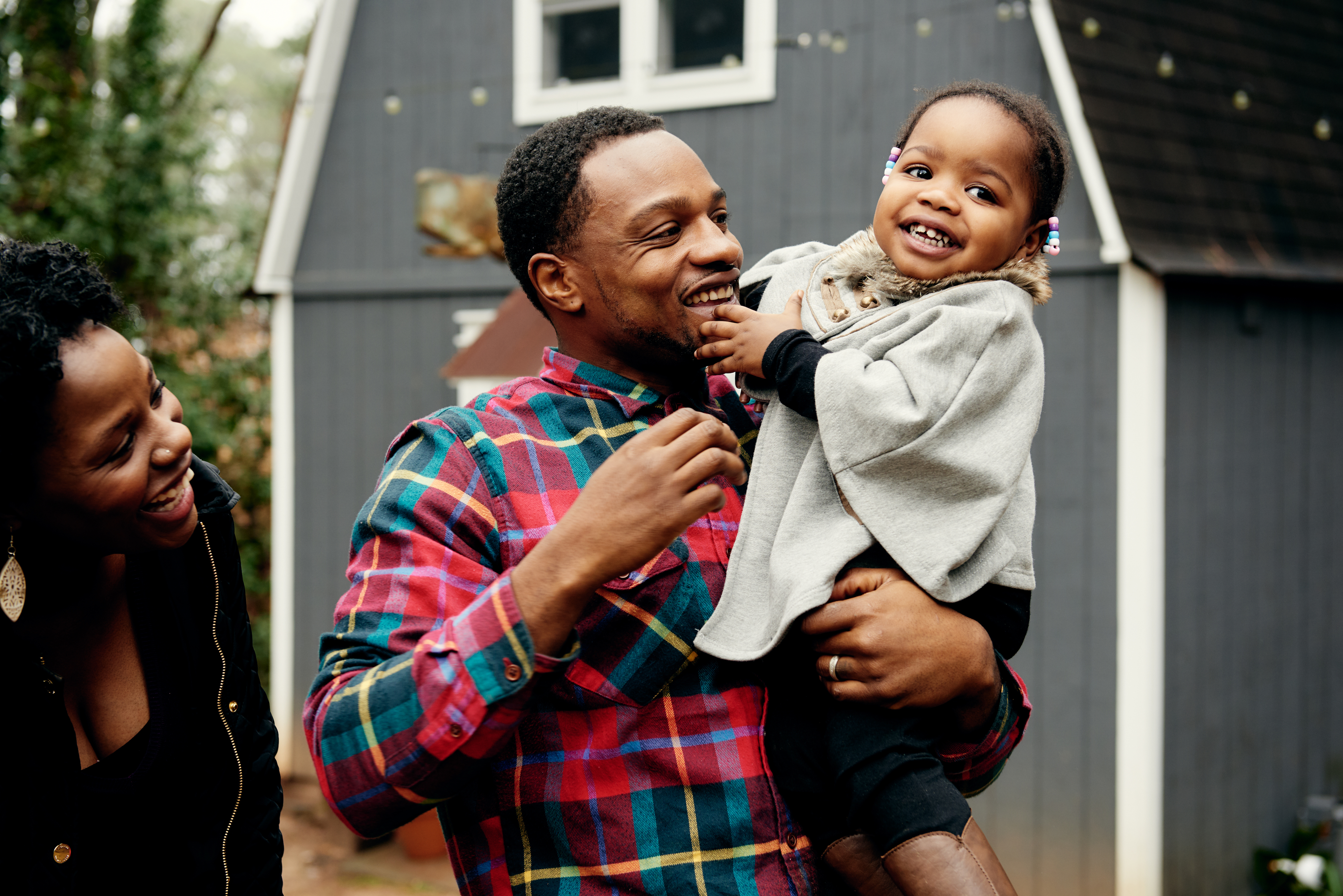 Smiling family with woman standing next to man holding baby girl