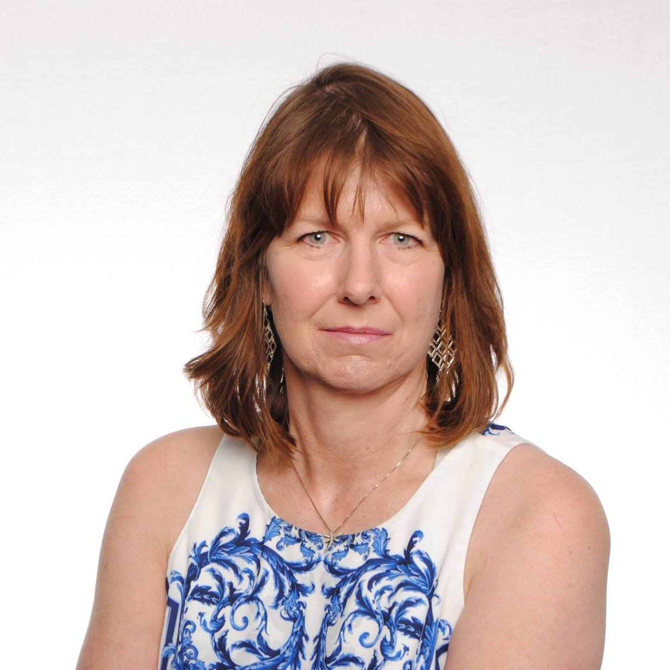 A headshot of Leslie, wearing a white tanktop with a blue pattern against a white backdrop.