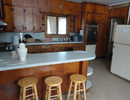 A photo of the old Filomena kitchen with all wood cabinets and dated appliances.