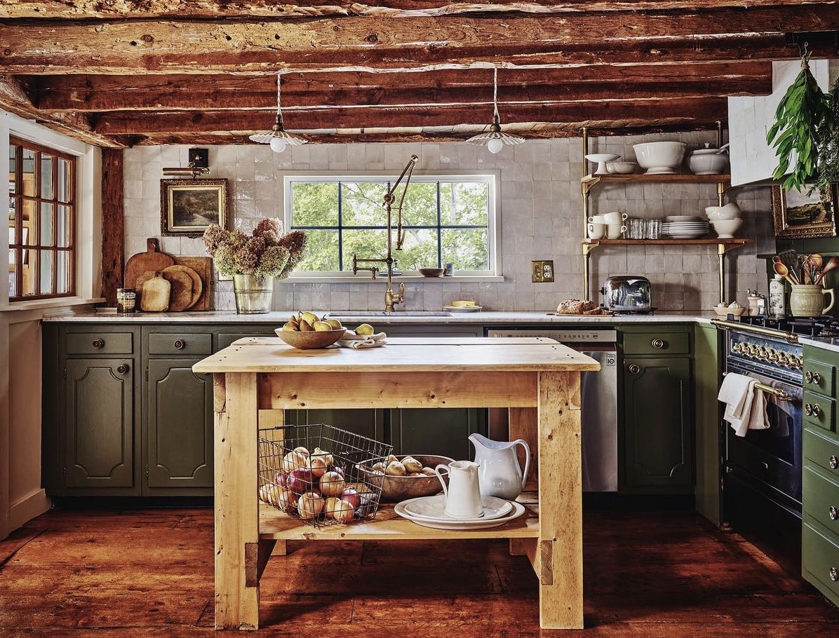 The renovated farmer's kitchen with an oak wood island, new green cabinetry and bone colored tile backsplahs with all new appliances and shelving.