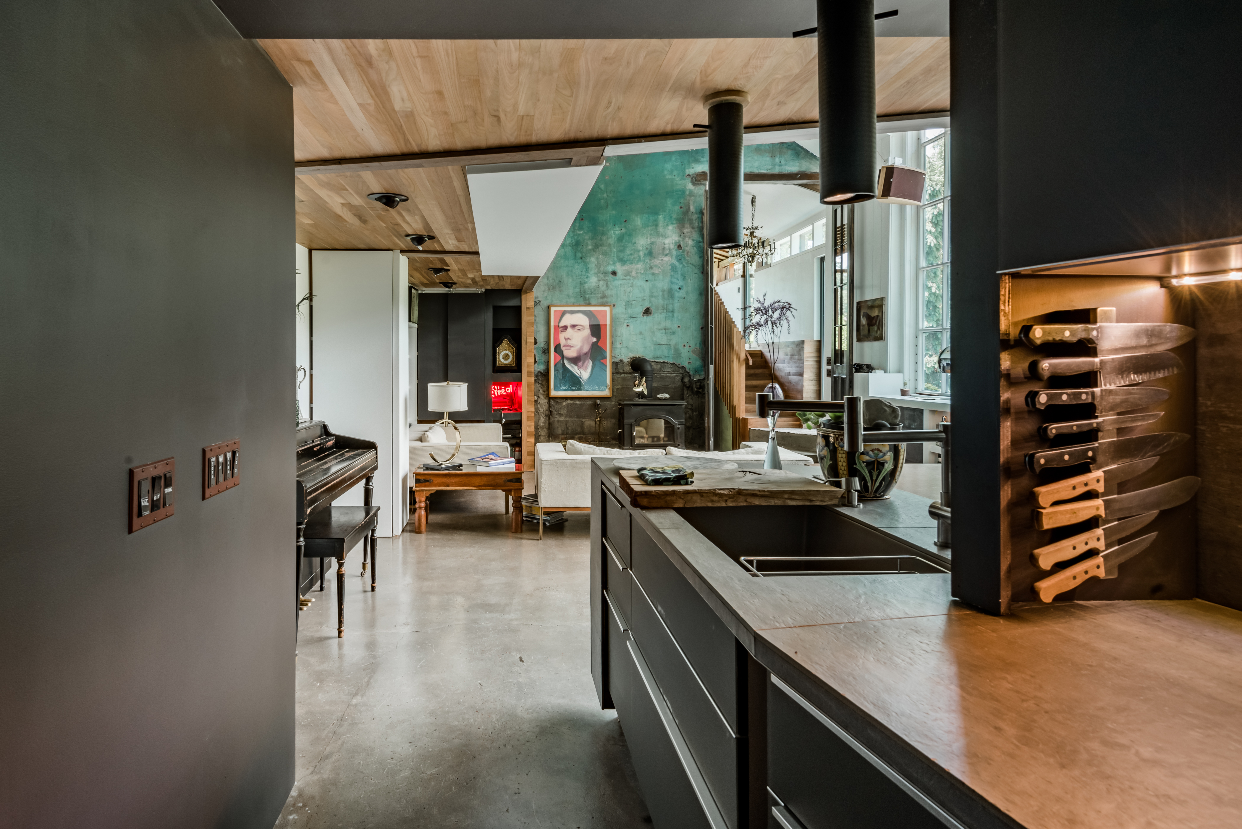 The Pond House kitchen shot from the galley kitchen. Shows a view looking onto a living area with floor to ceiling windows and eclectic art.