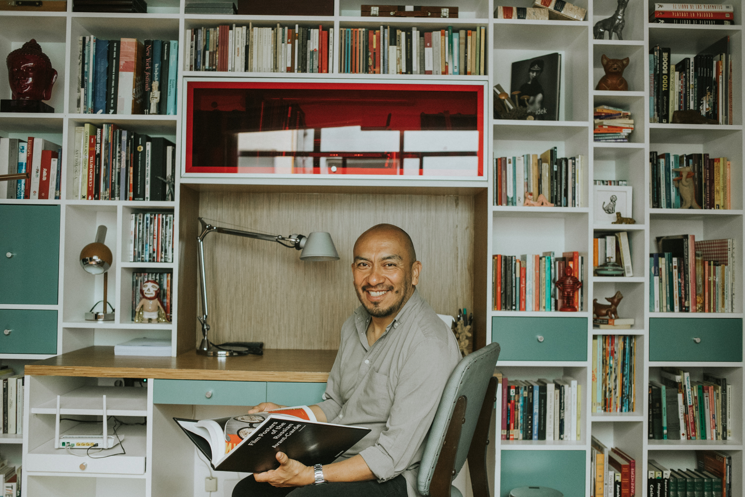 Marco, anfitrion mexicano posando sonriente en la biblioteca de su casa