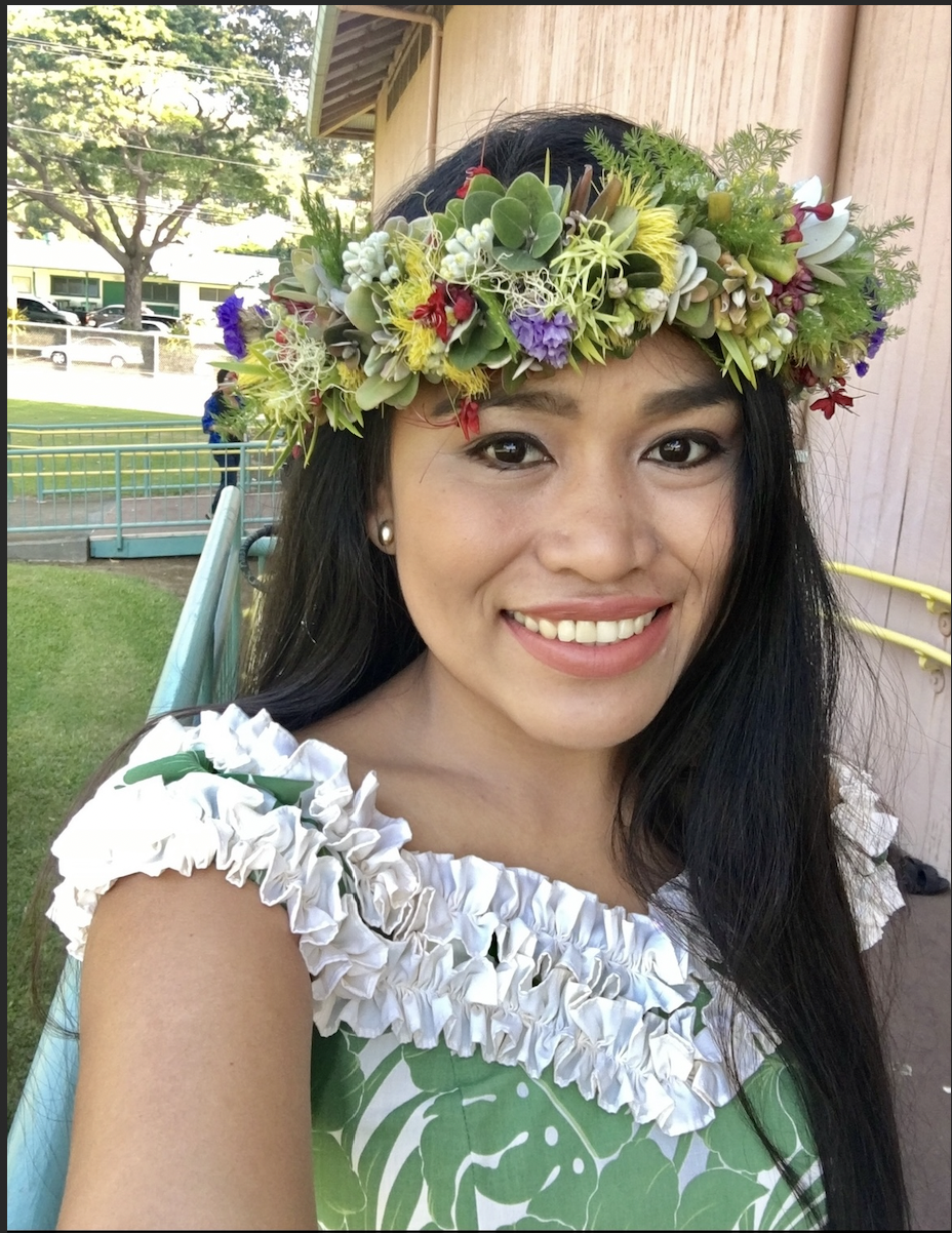 Woman posing for a selfie and smiling, wearing a flower crown. 