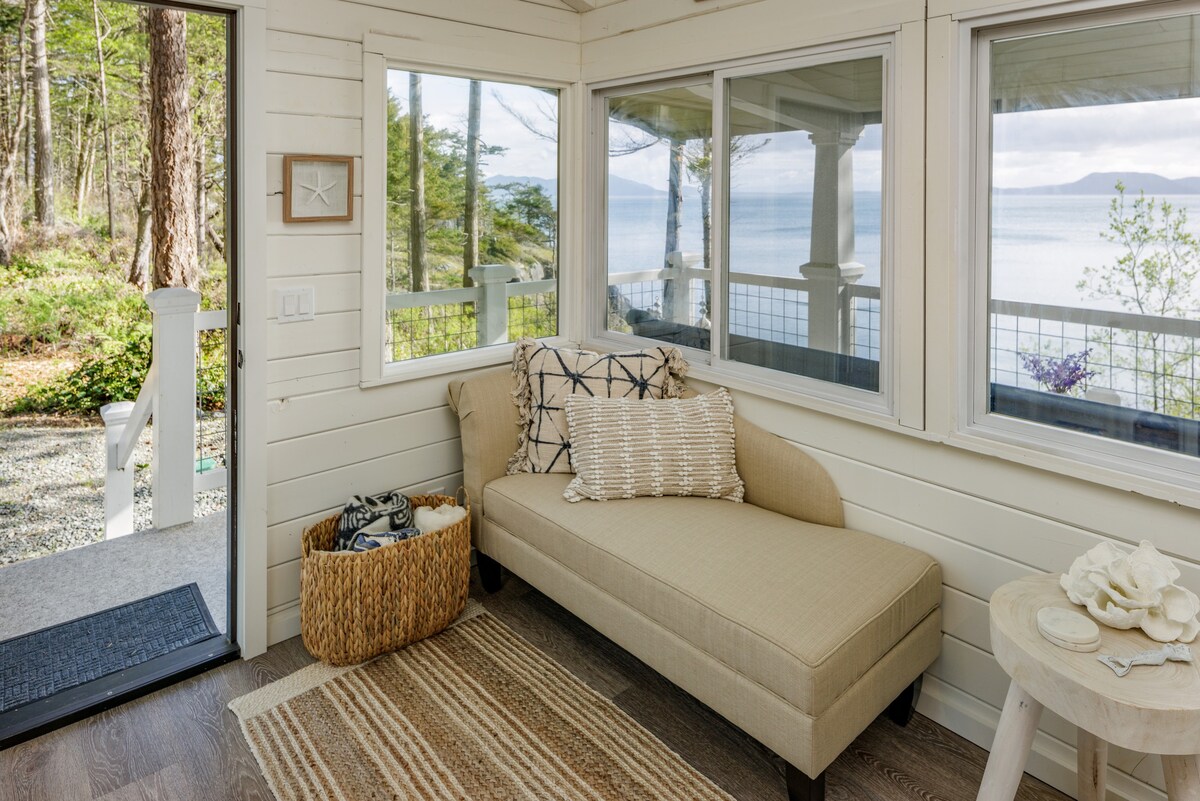 A sitting area with a cream couch looking out to the view of the ocean.
