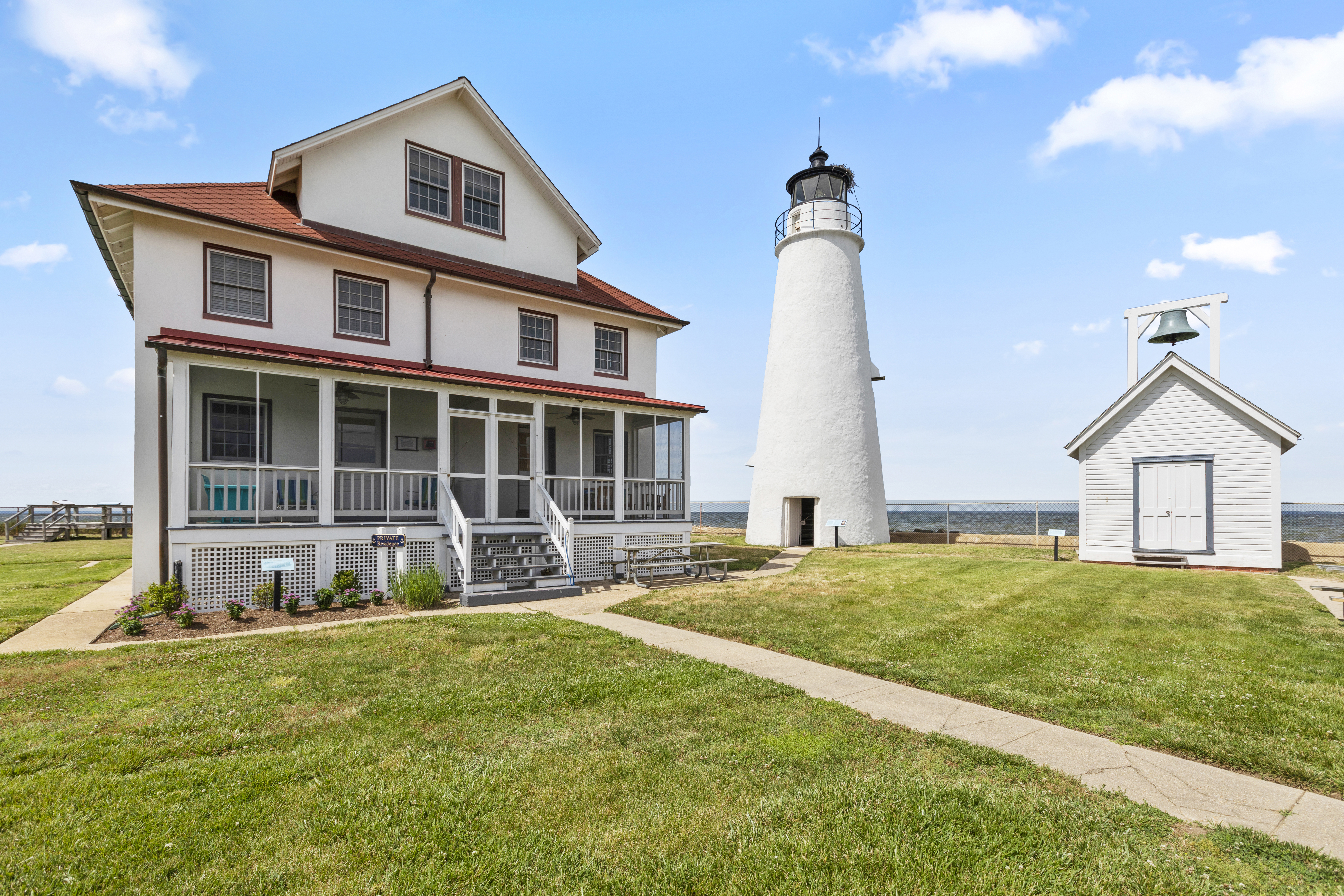 A lighthouse and light-keeper cottage on a grassy field in Cove Point.