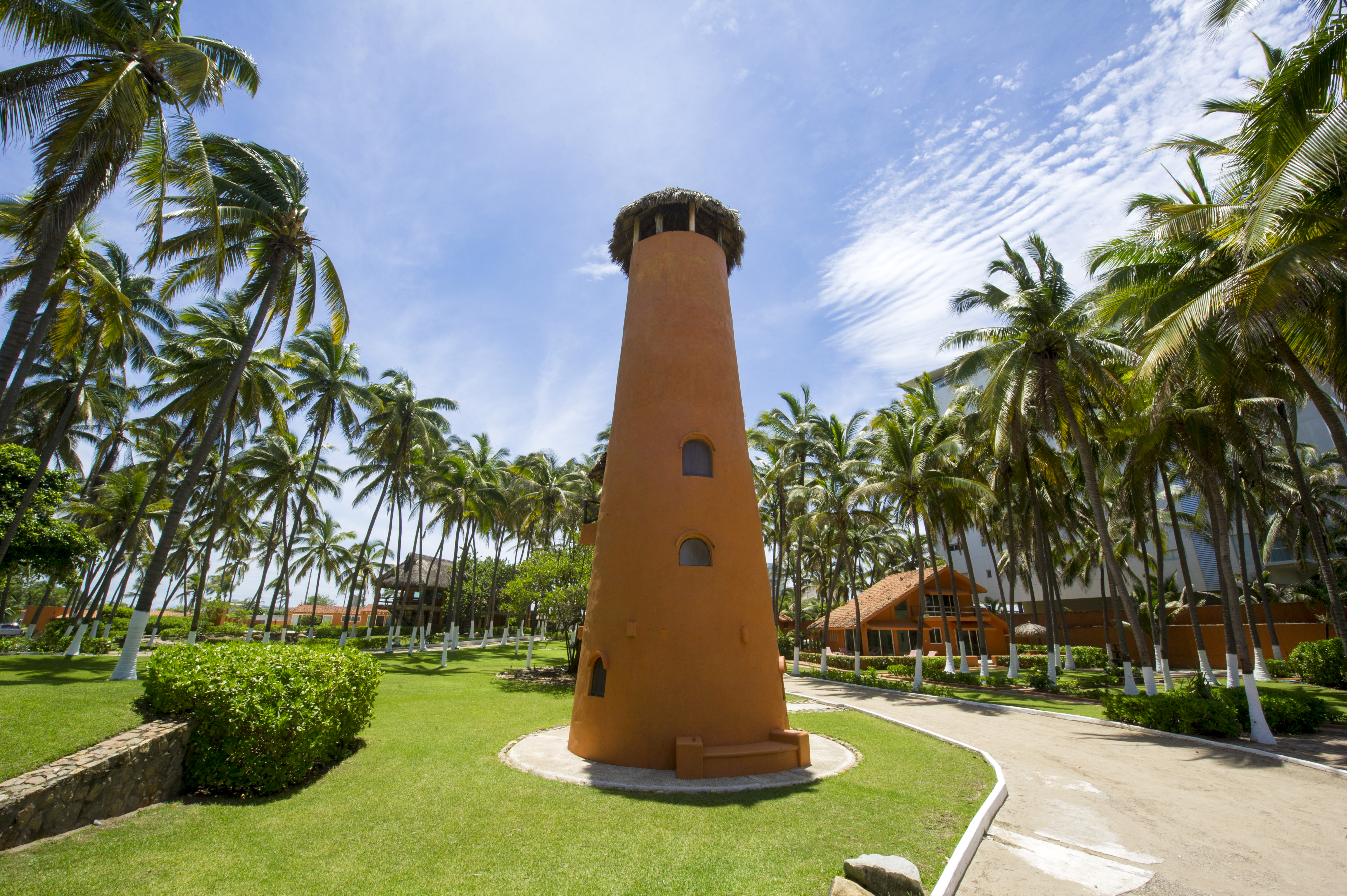 A clay faro surrounded by palm trees.