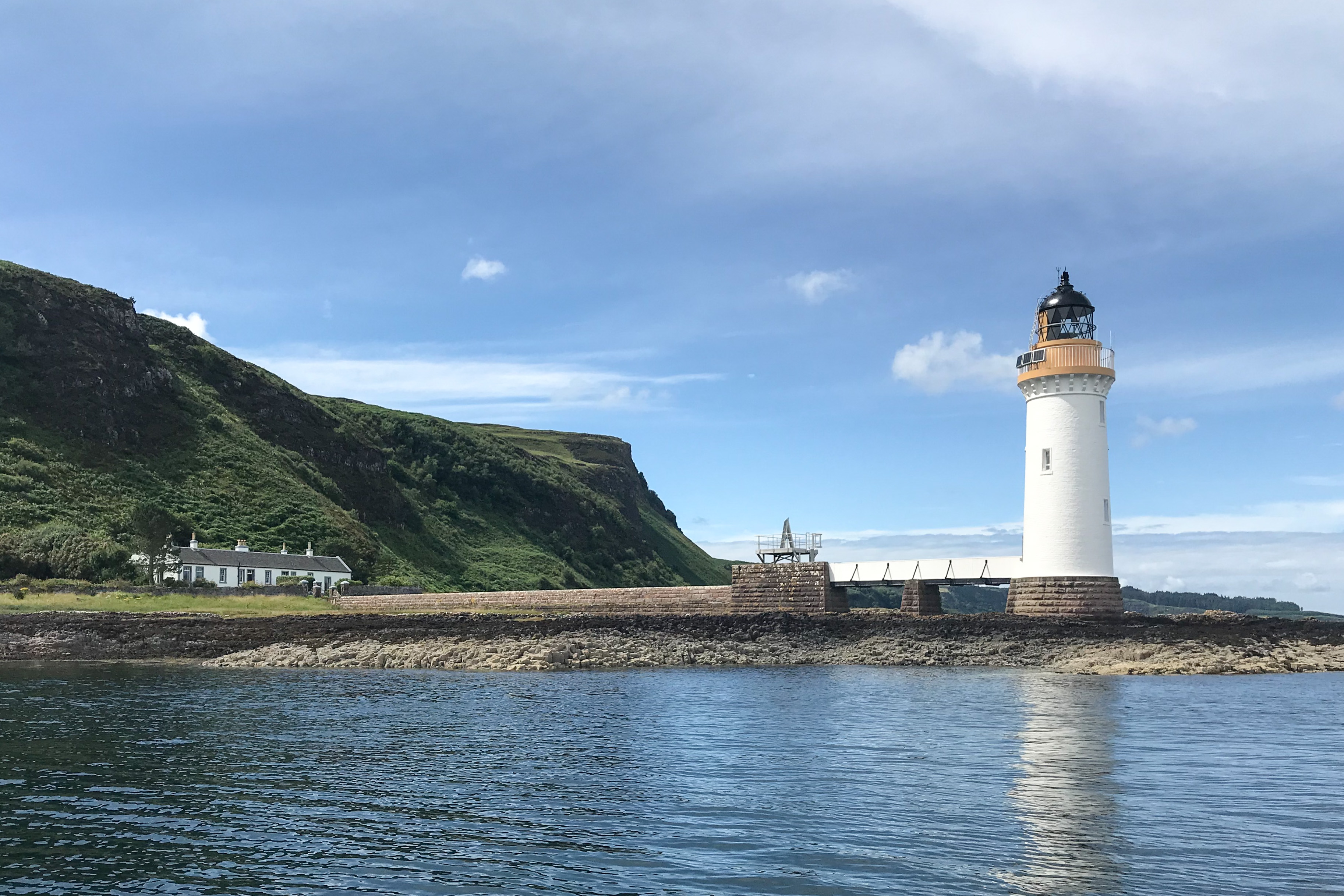 A gold and white lighthouse on a bay.