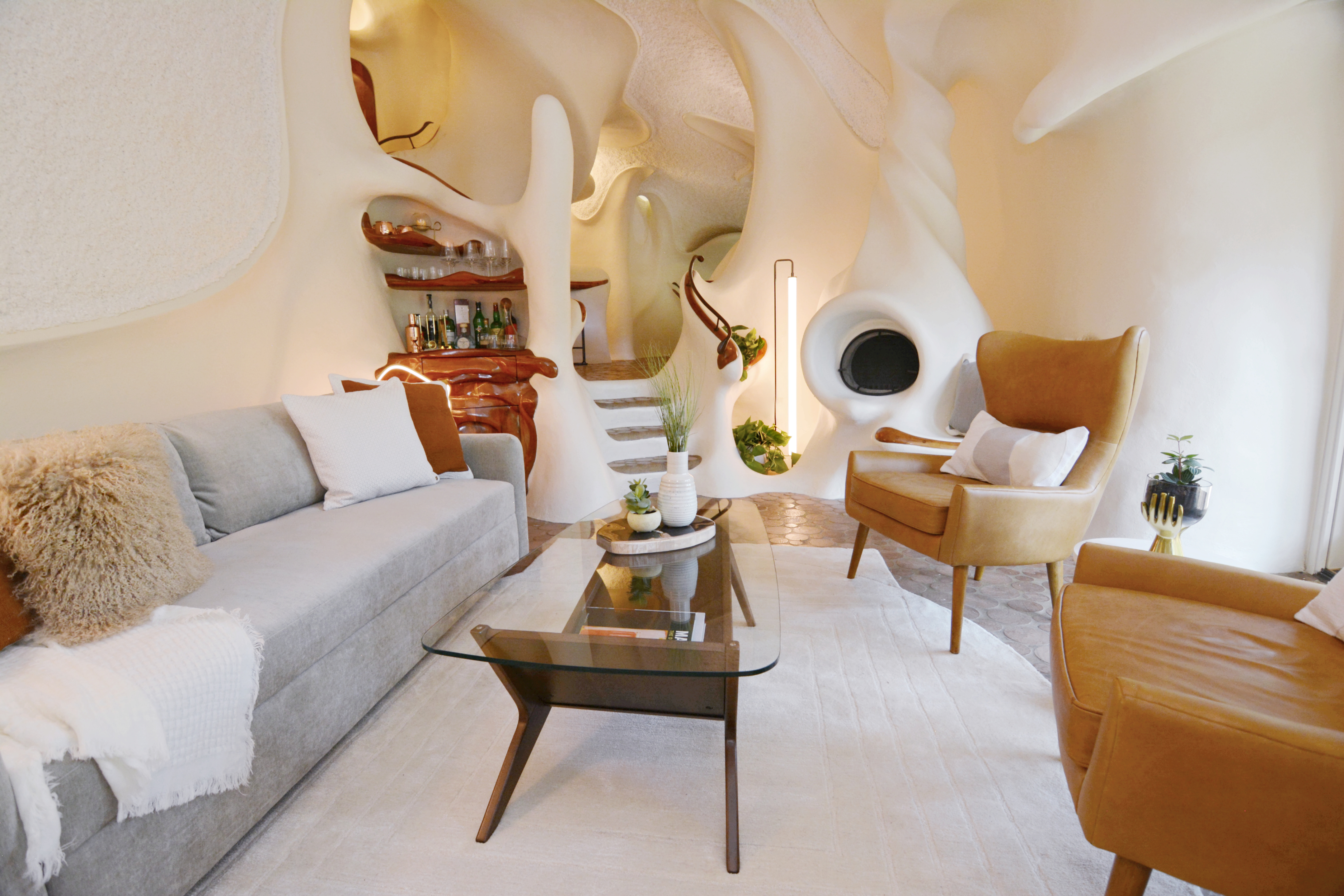 A white walled living room with mid-century modern furniture in the foreground and  whimsical interior architecture surrounding it.