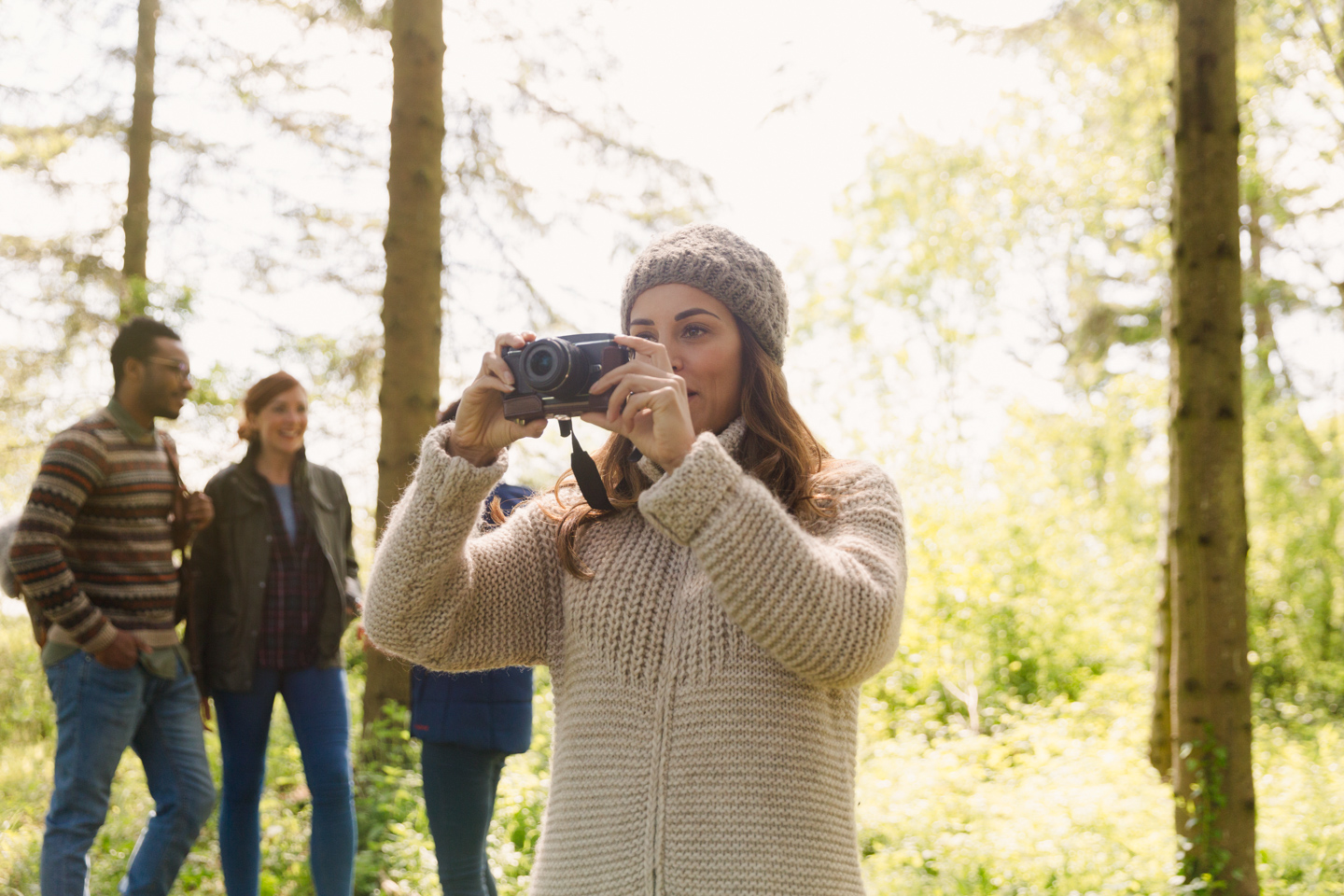 Mujer usando una camara en medio de una caminata en el bosque