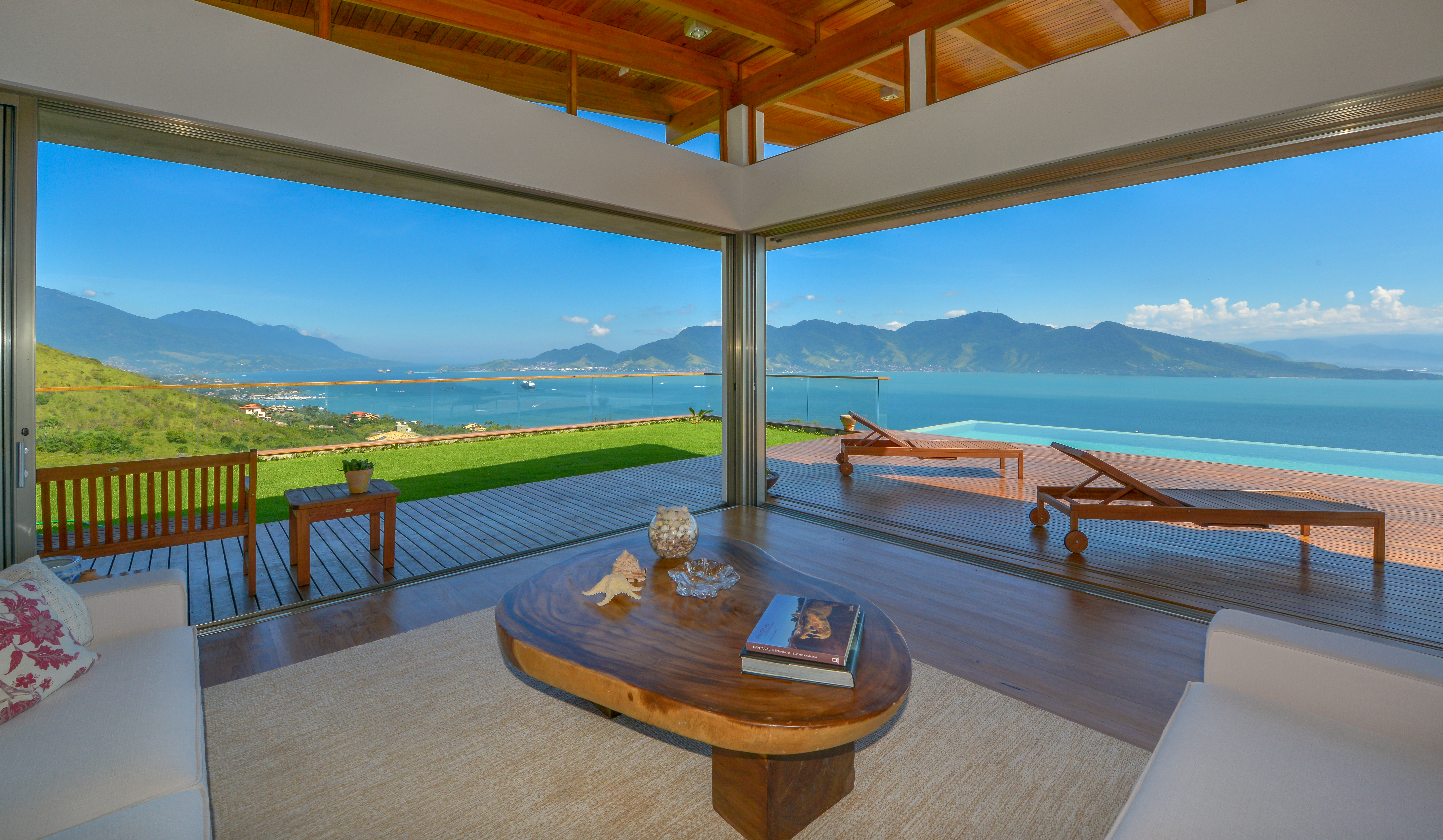 A modern living room with an attached pool, overlooking a crisp blue ocean