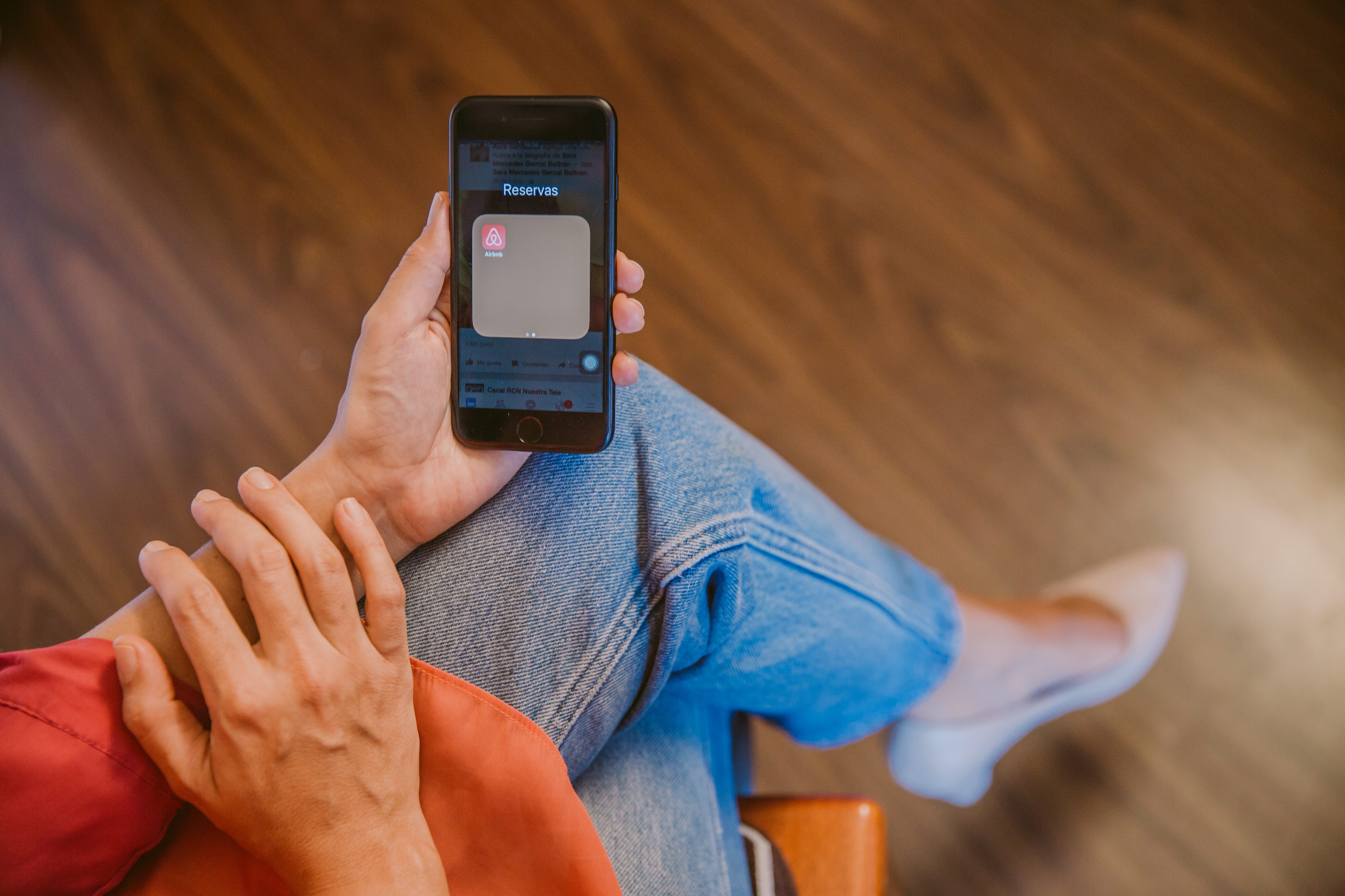Mujer sostiene su celular y se ve la aplicacion de Airbnb en la pantalla