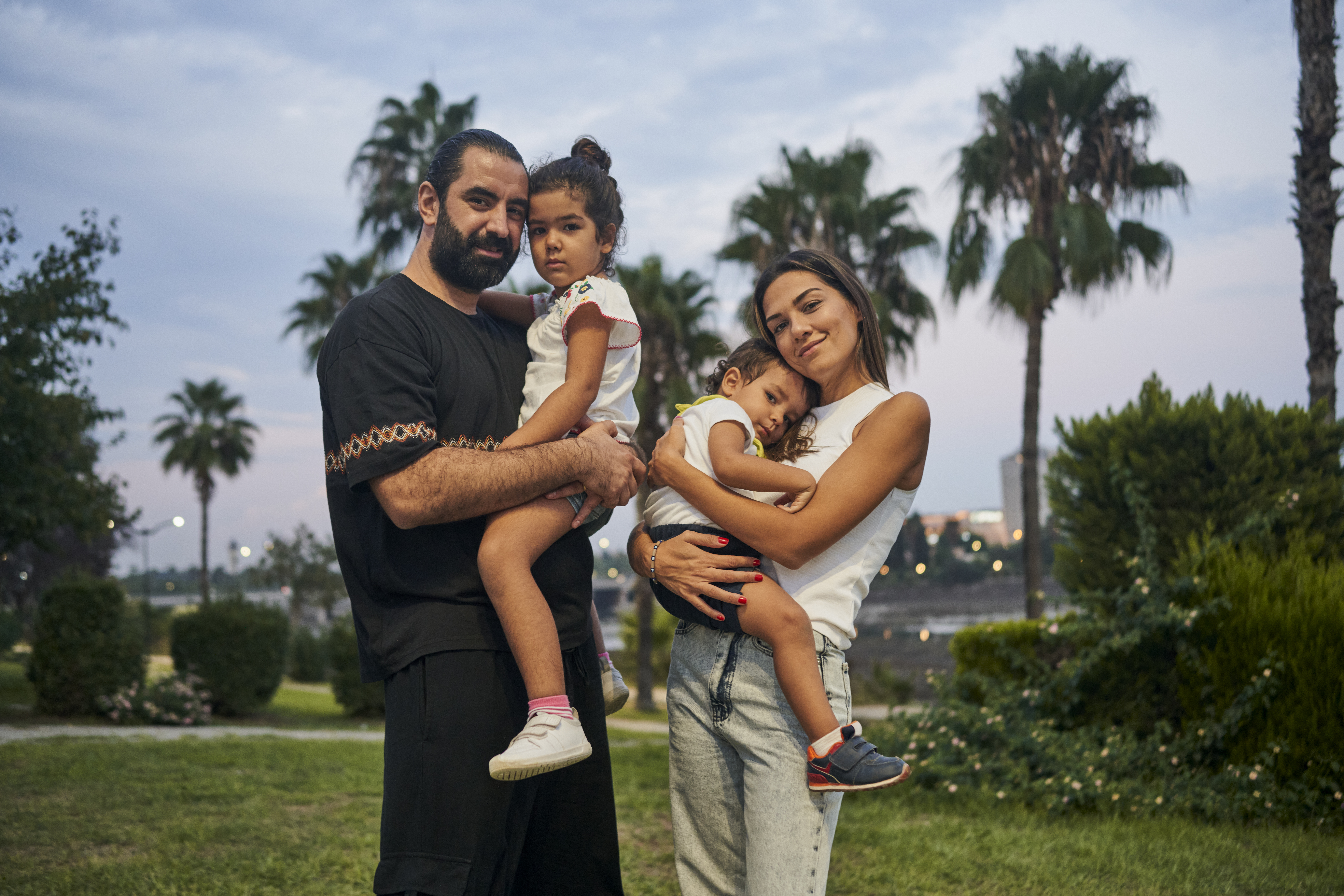 Man and woman stand next to one another, each holding one of their daughters