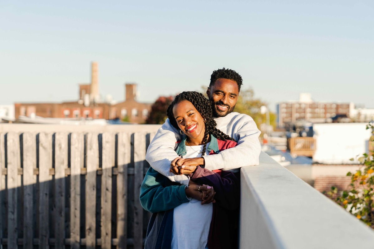 Smiling man hugs smiling woman on a balcony