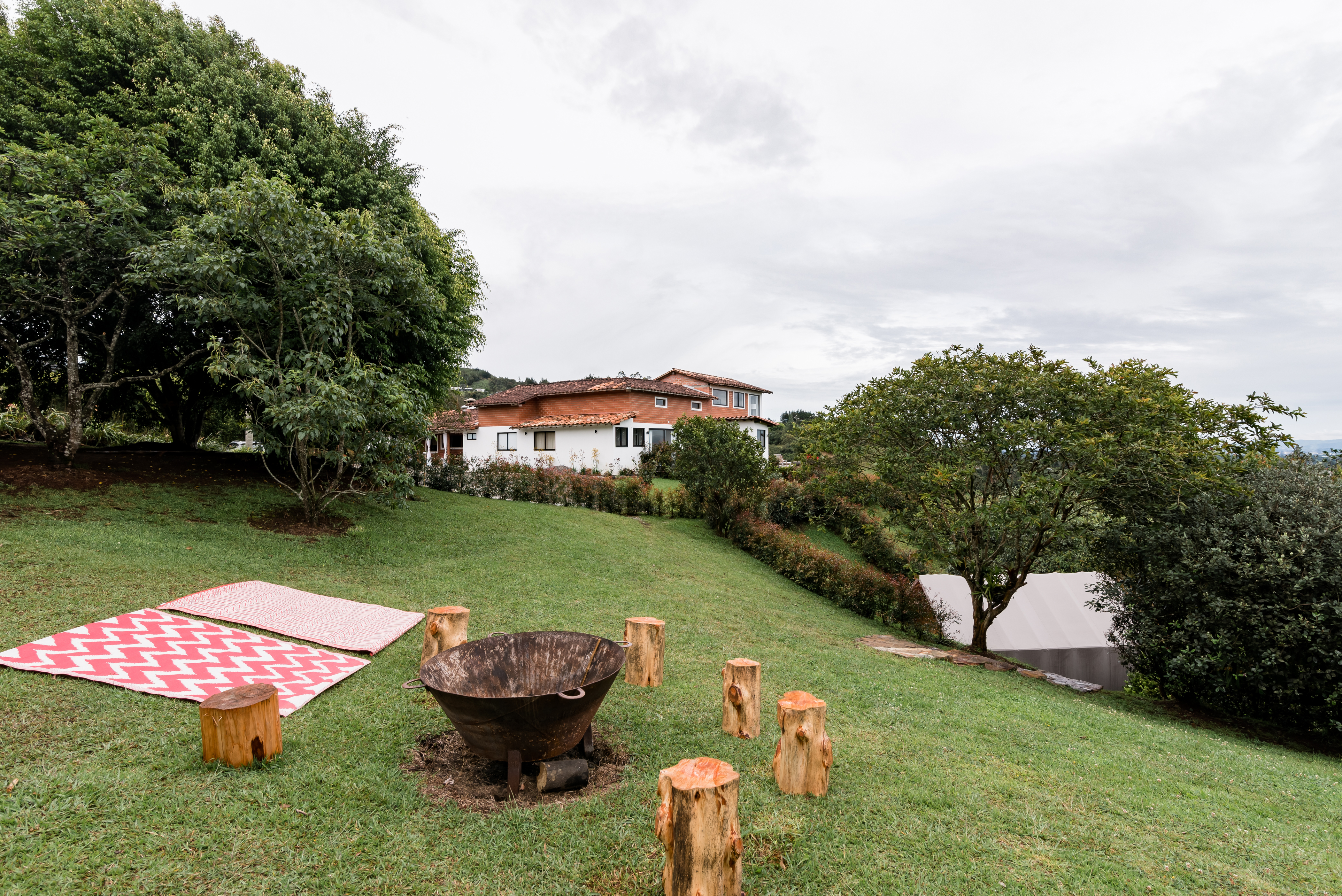 View of a picnic mat in the grass with a visual of a white house in the center surrounded by trees