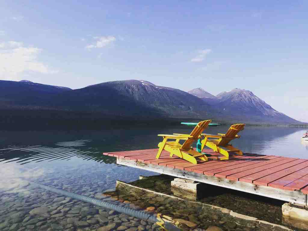 A dock with Muskoka chairs overlooking a quiet lake.