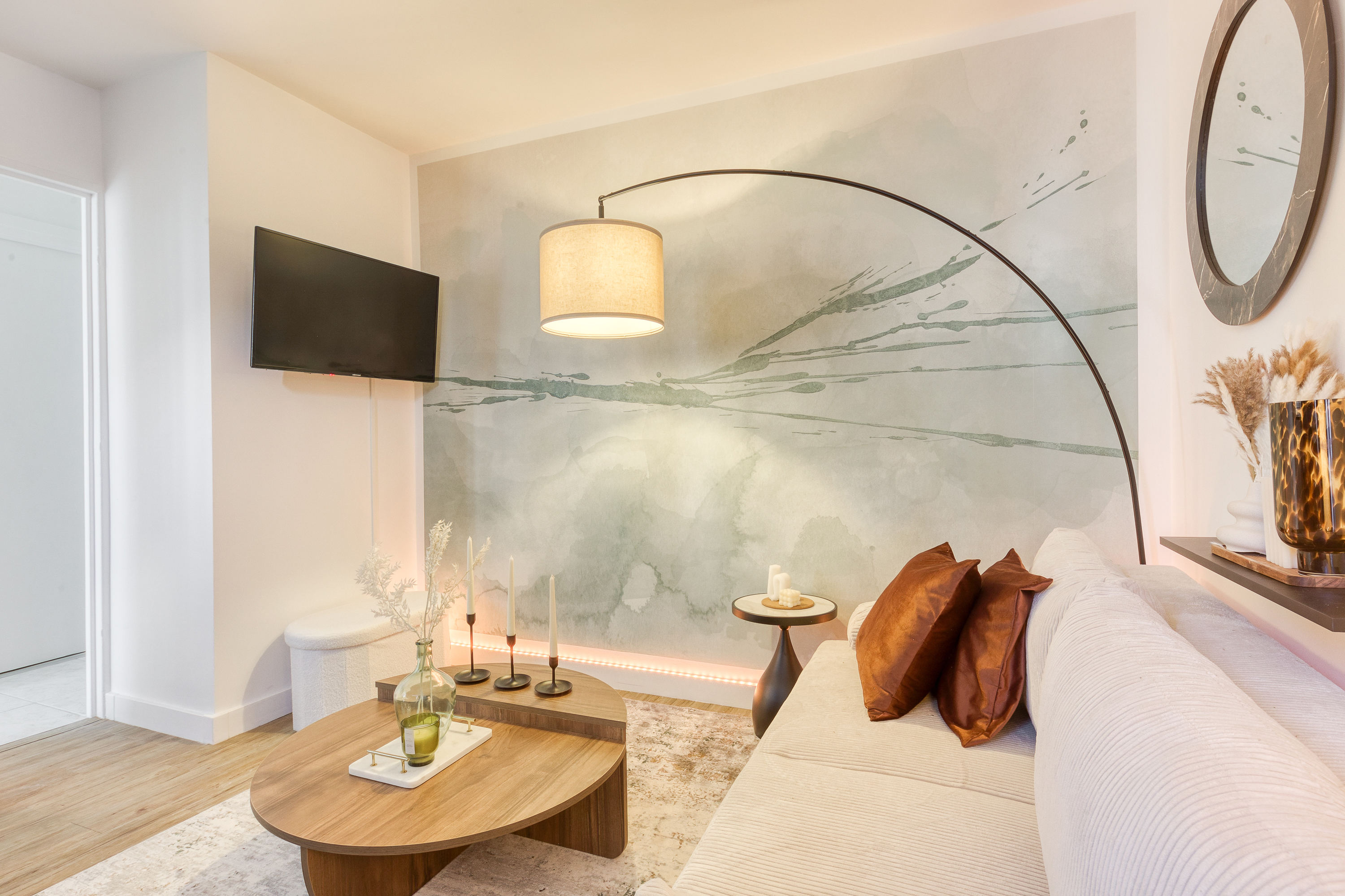 A stylish living room in an apartment located just outside Paris. White sofa, modern oval coffee table and a feature wall paint-splatter wallpaper.
