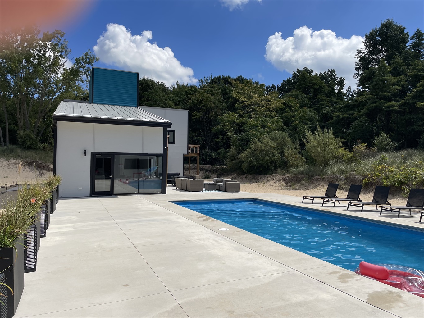 Modern zinc roofed bungalow nestled among the dunes surrounded by nature and lush greenery. Pool in foreground