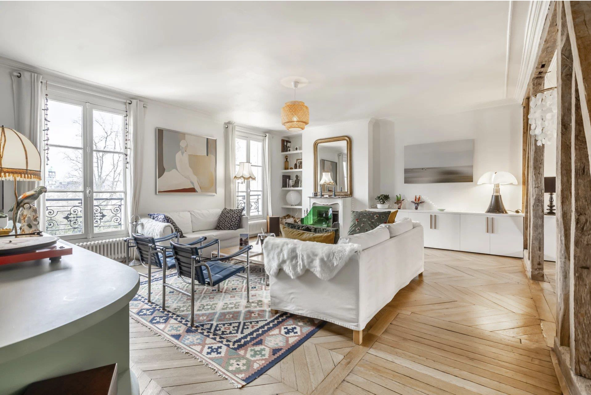 Light-filled livingroom with parquet flooring, white sofa and designer chairs in the St Germain des Pres neighbourhood of Paris. 