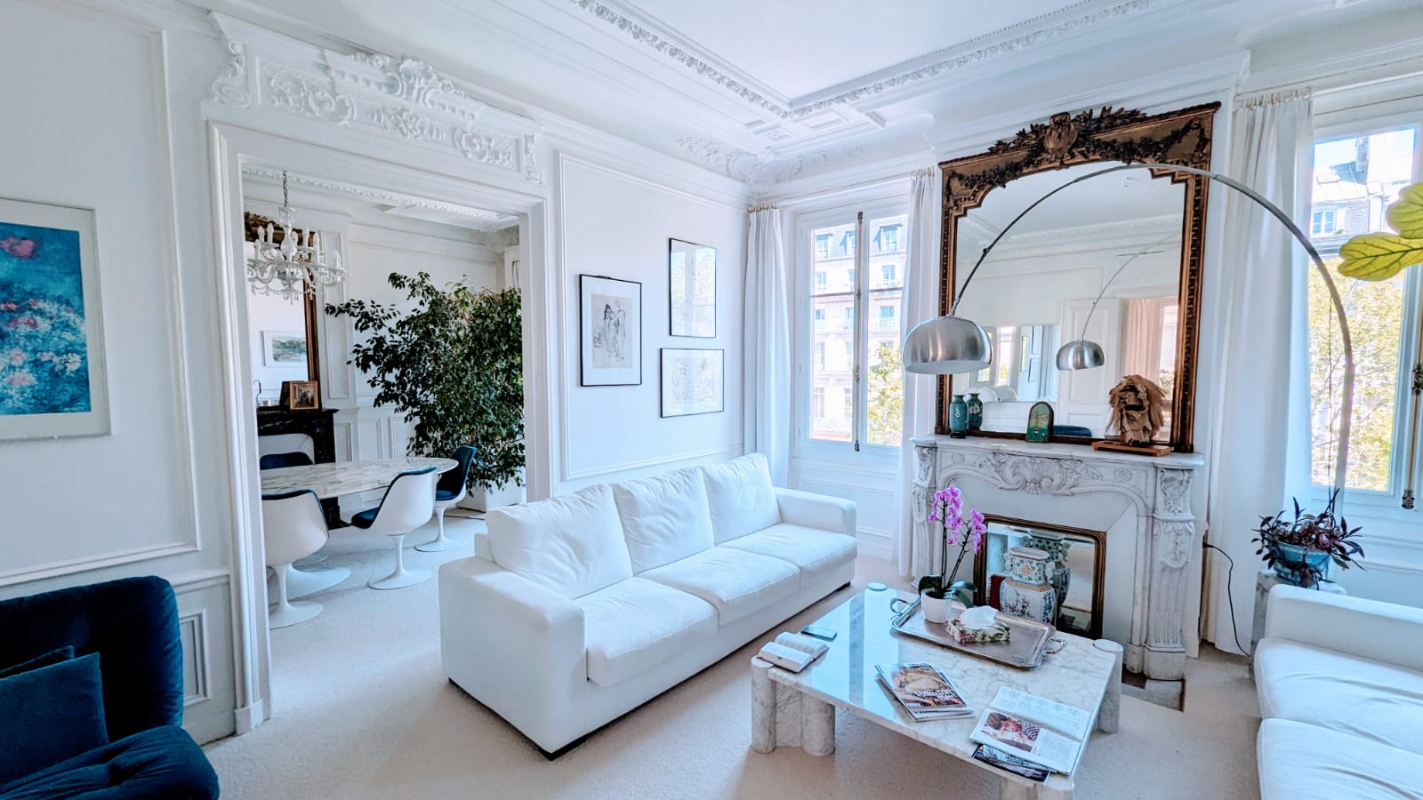 Large and luxious apartment in the Le Marais neighborhood of Paris. View of a white living room: white marble fireplace, white sofa and white walls.
