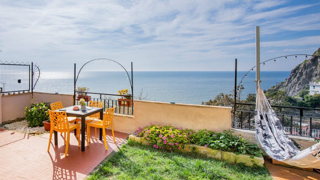 Patio with tables and chairs and a hammock overlooking the sea