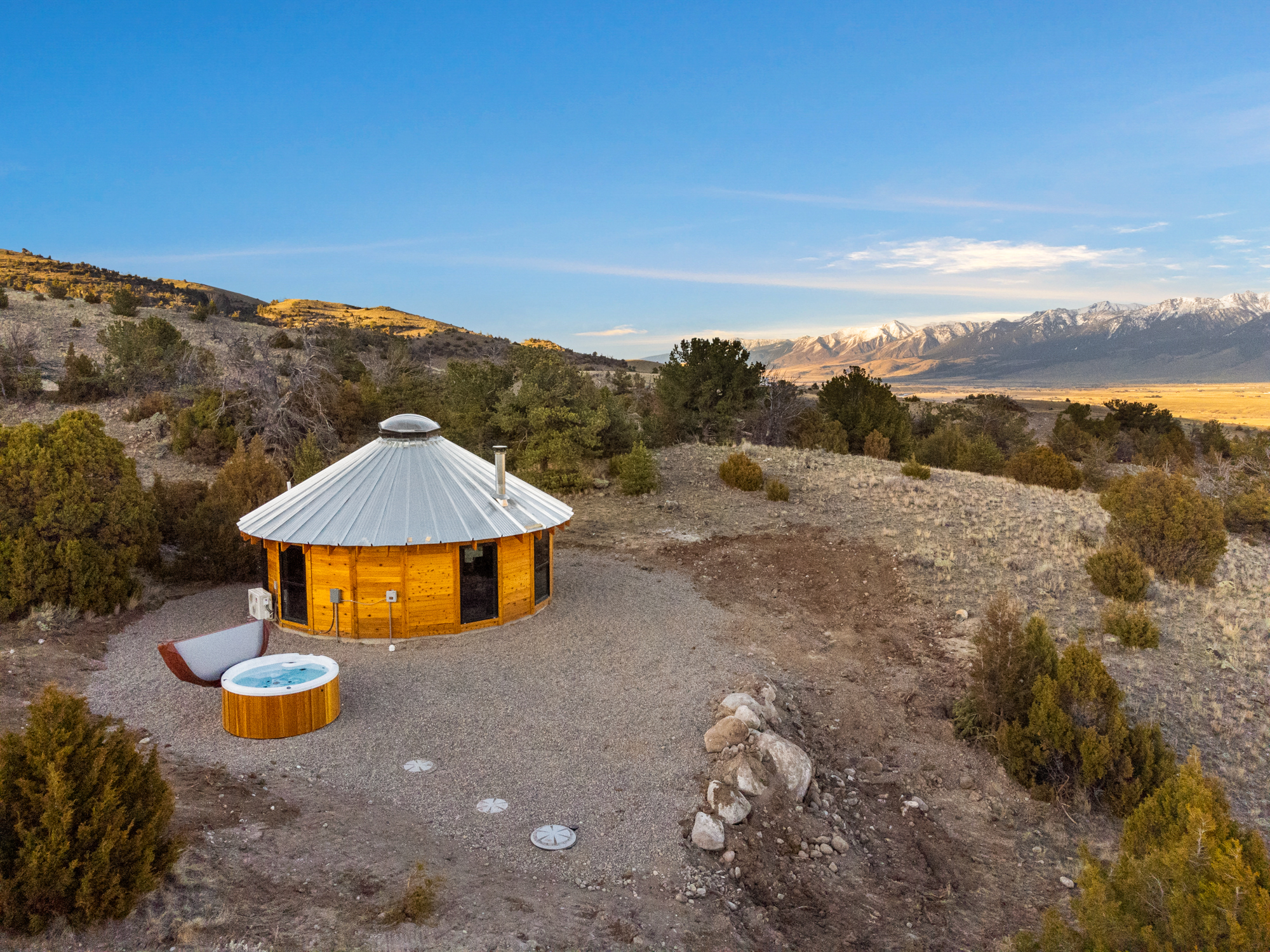 A wooden mountain yurt surrounded by mountains