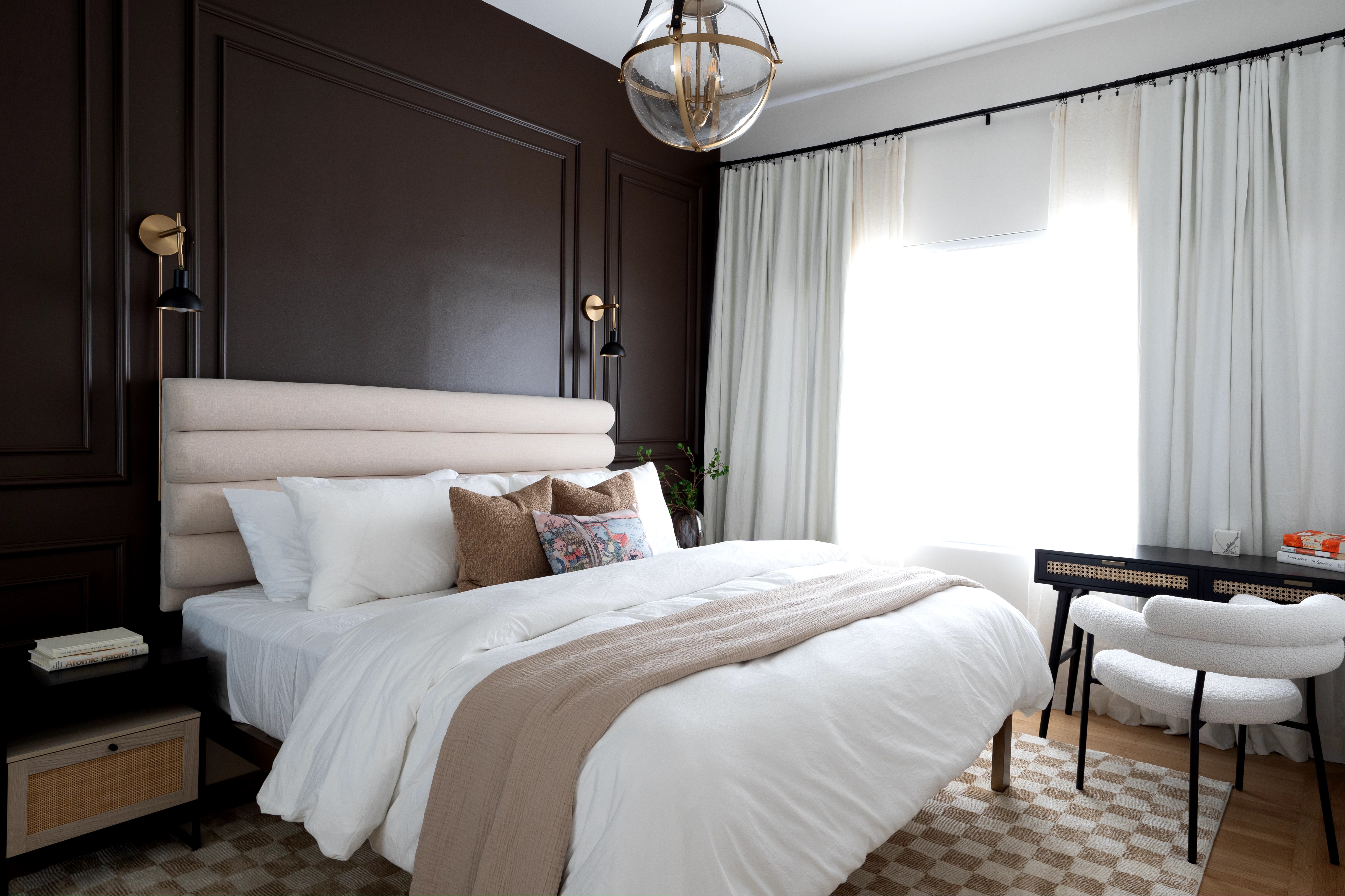 Stylish bedroom featuring a beige headboard, bedside lamps, and a patterned rug under a spacious bed.