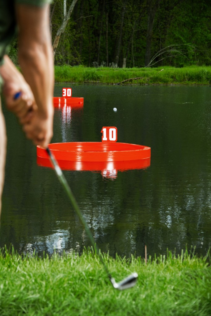 Golf club and ball in foreground, aimed at numbered floating targets 10 and 30 on a pond.