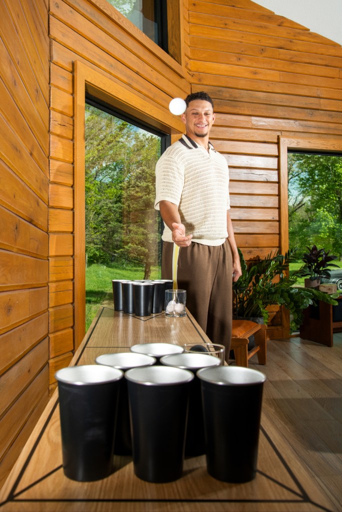 Ping pong ball in mid-air as a person stands ready in a sunlit wooden interior with cups lined up on either side of a table.