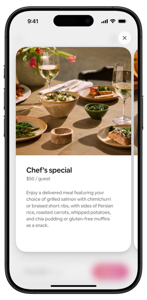 Smartphone screen showing a visual of the Chef's table offering, including a table setup featuring a chef's special with white wine, mixed salads, and main dishes elegantly plated.