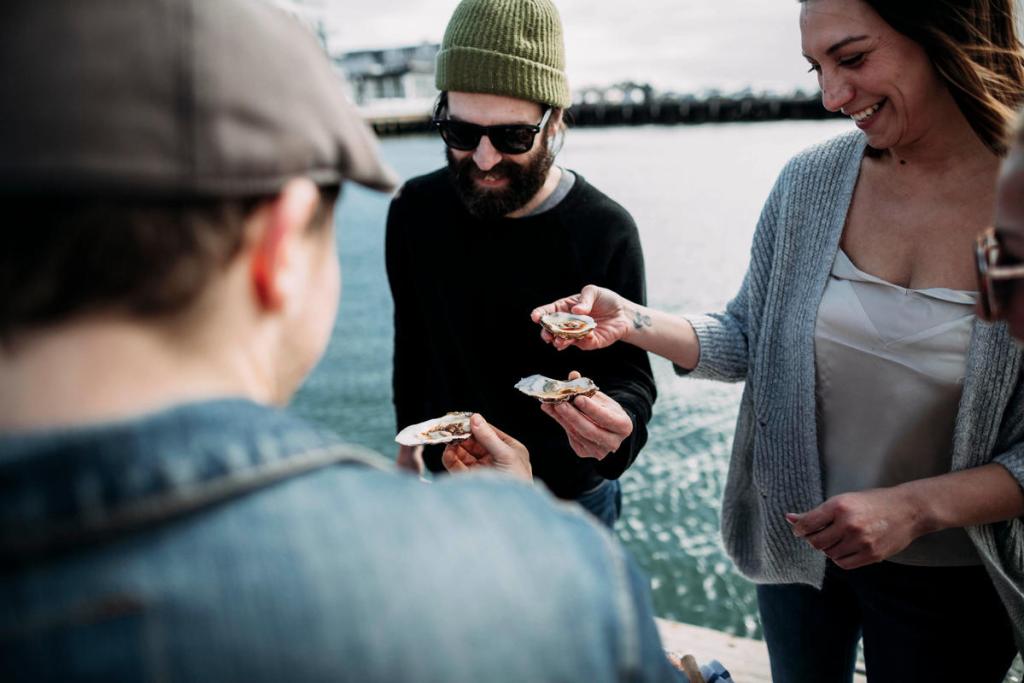 3 people with oysters by the water