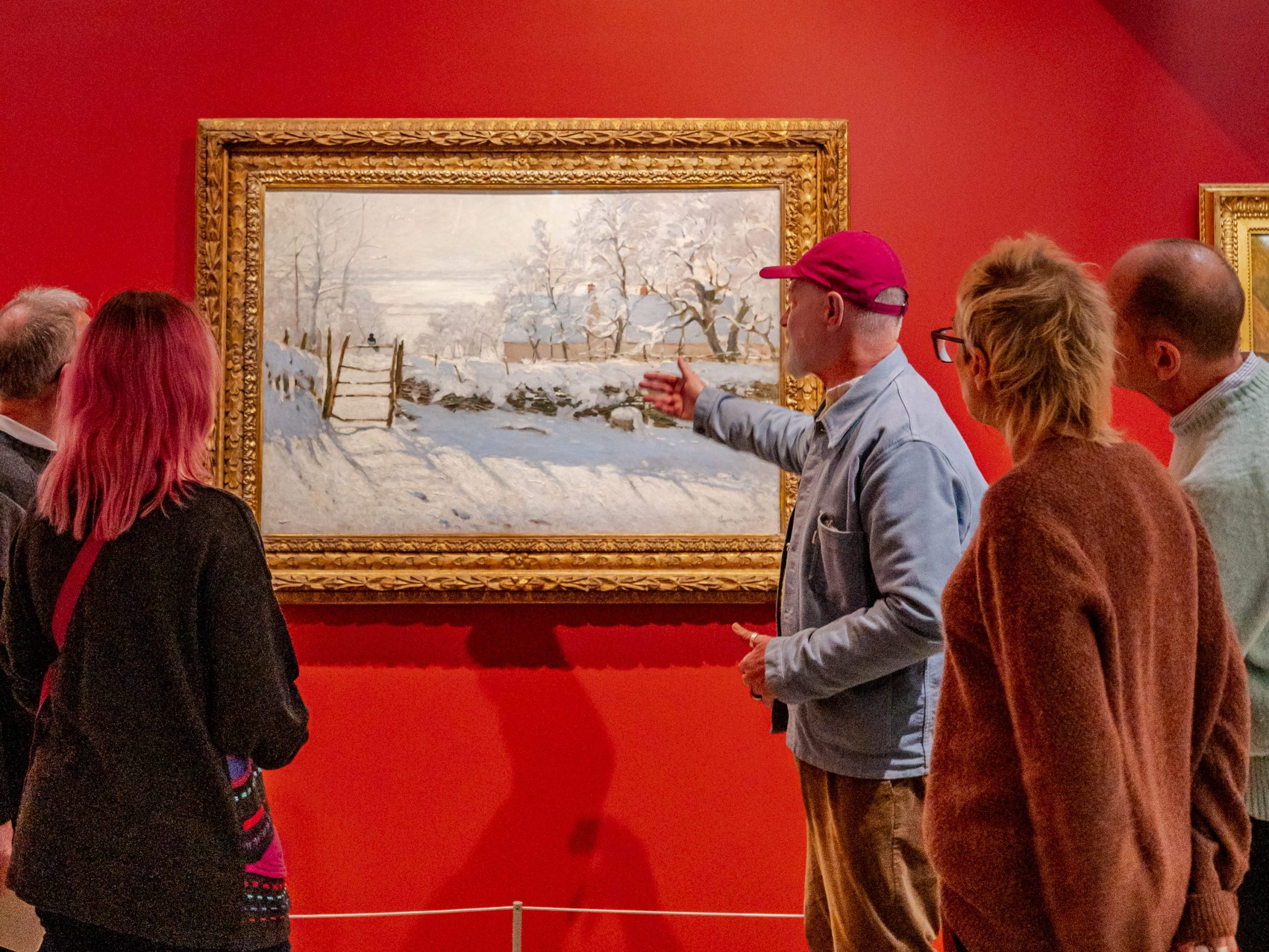 Group of people standing in front of a painting with a red wall