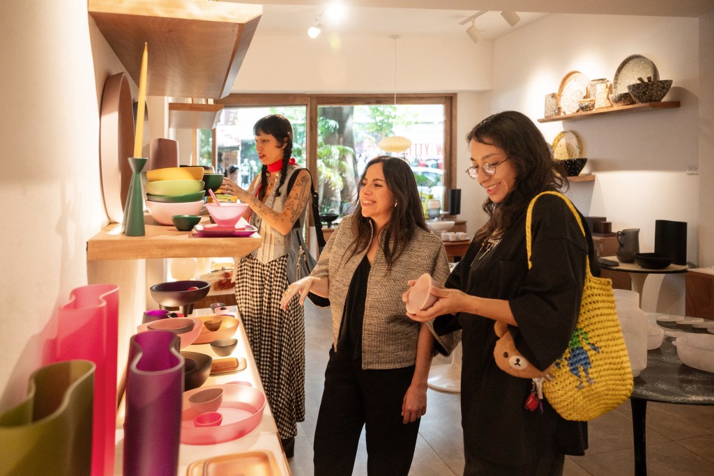 A pottery shop featuring various colorful ceramic pieces with three women shopping and interacting with the displays.