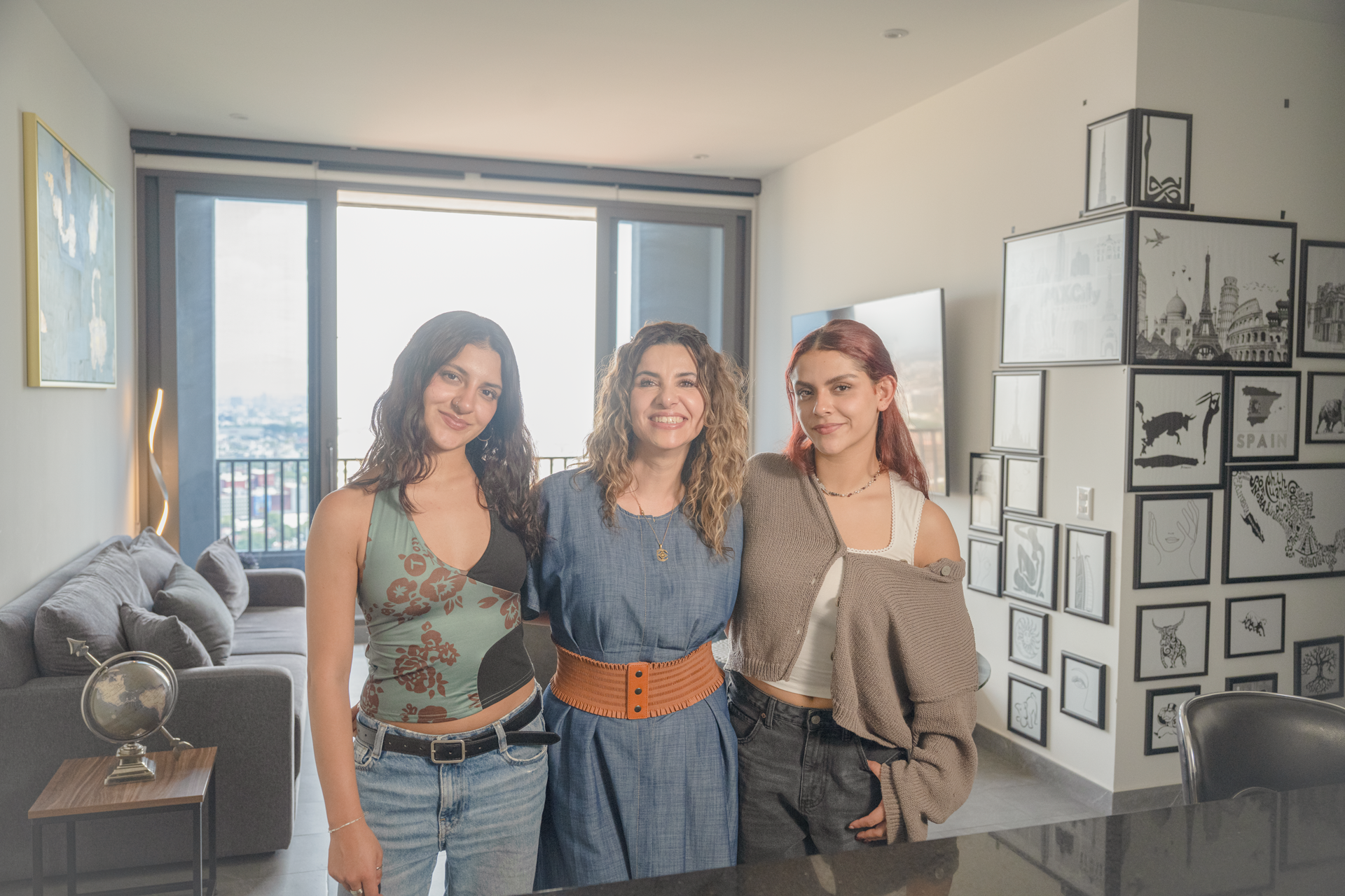 Tres mujeres abrazadas mirando a la cámara dentro de un apartamento