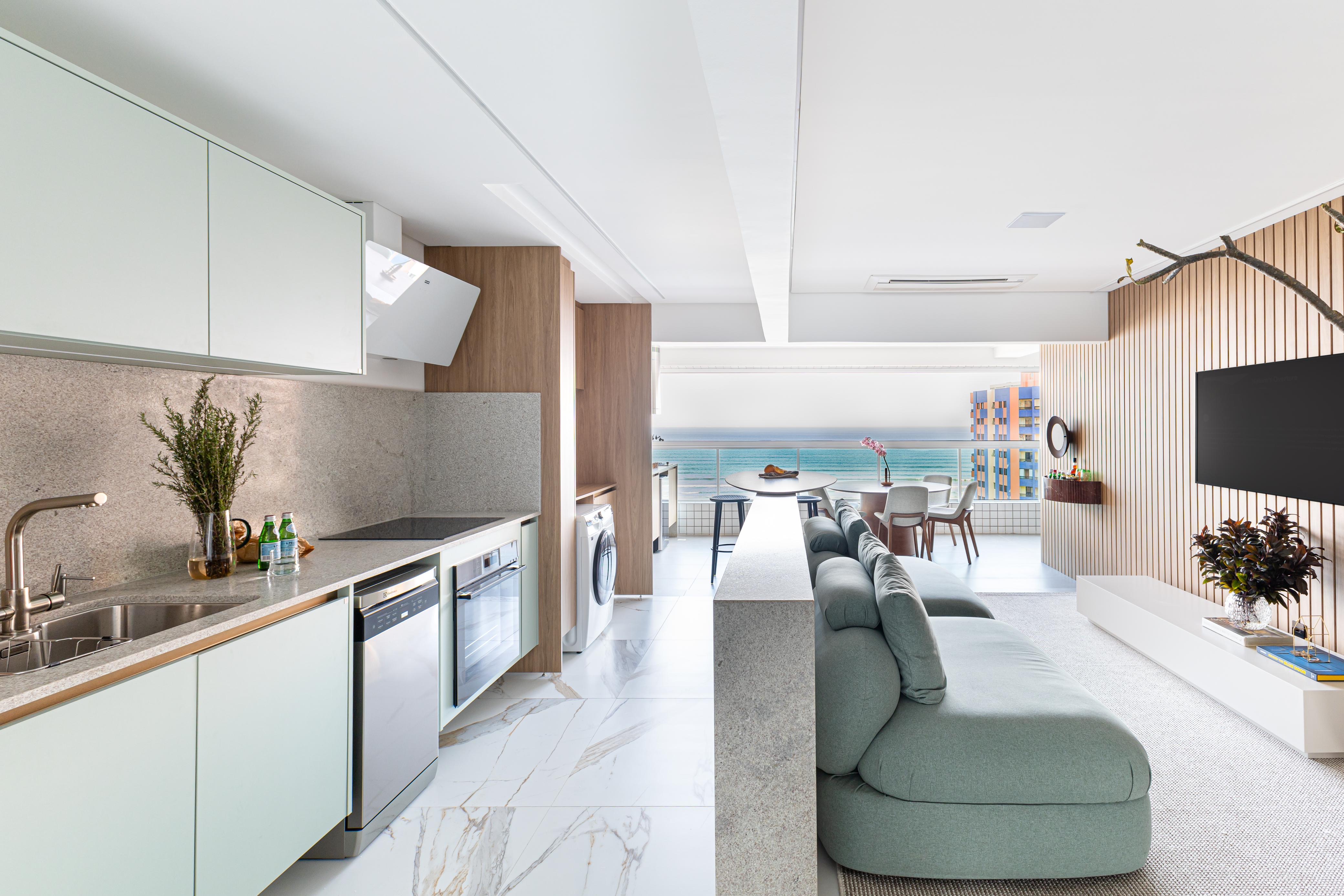 A sleek, open-concept apartment combines a contemporary kitchen and living area with ocean views through large windows.