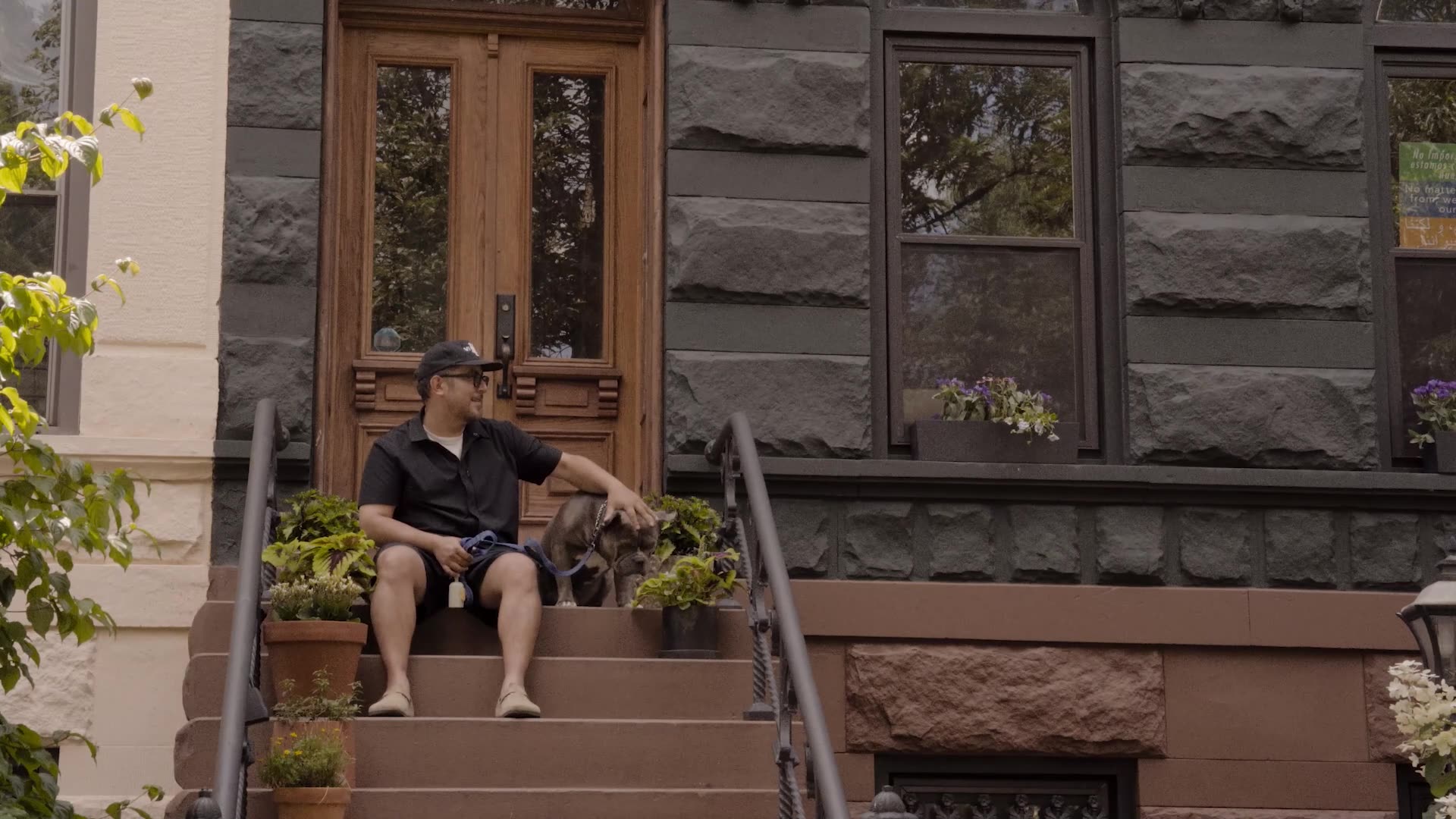 Man pets dog on stoop in front of home.