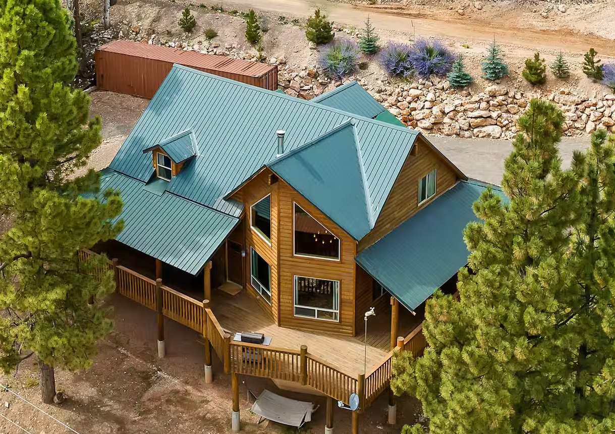 Large cabin surrounded by green trees.