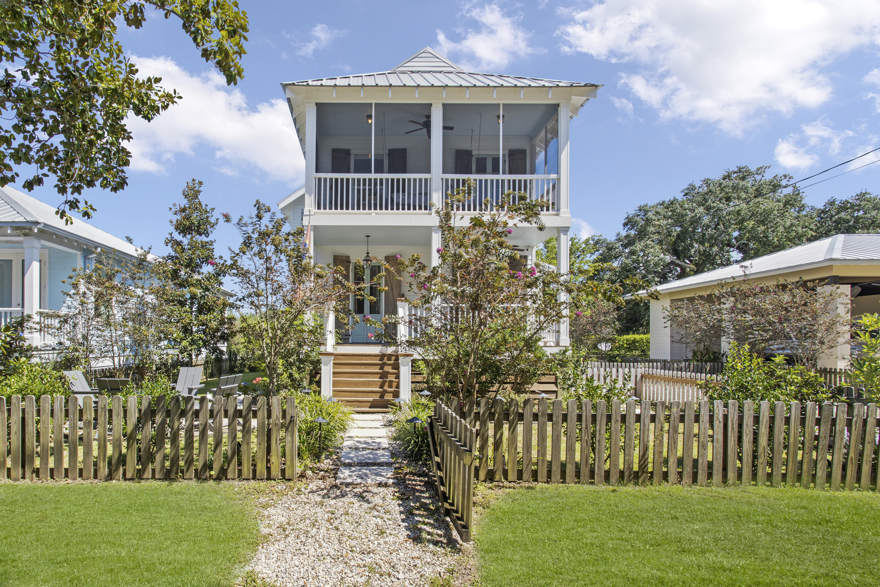 A beach bungalow with two porches surrounded by green grass.
