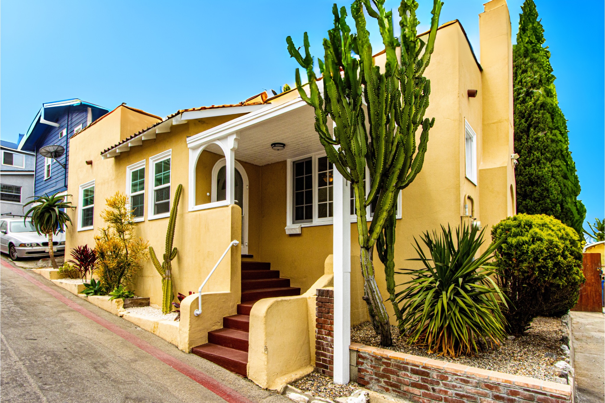 A yellow coastal home with cacti surrounding it.