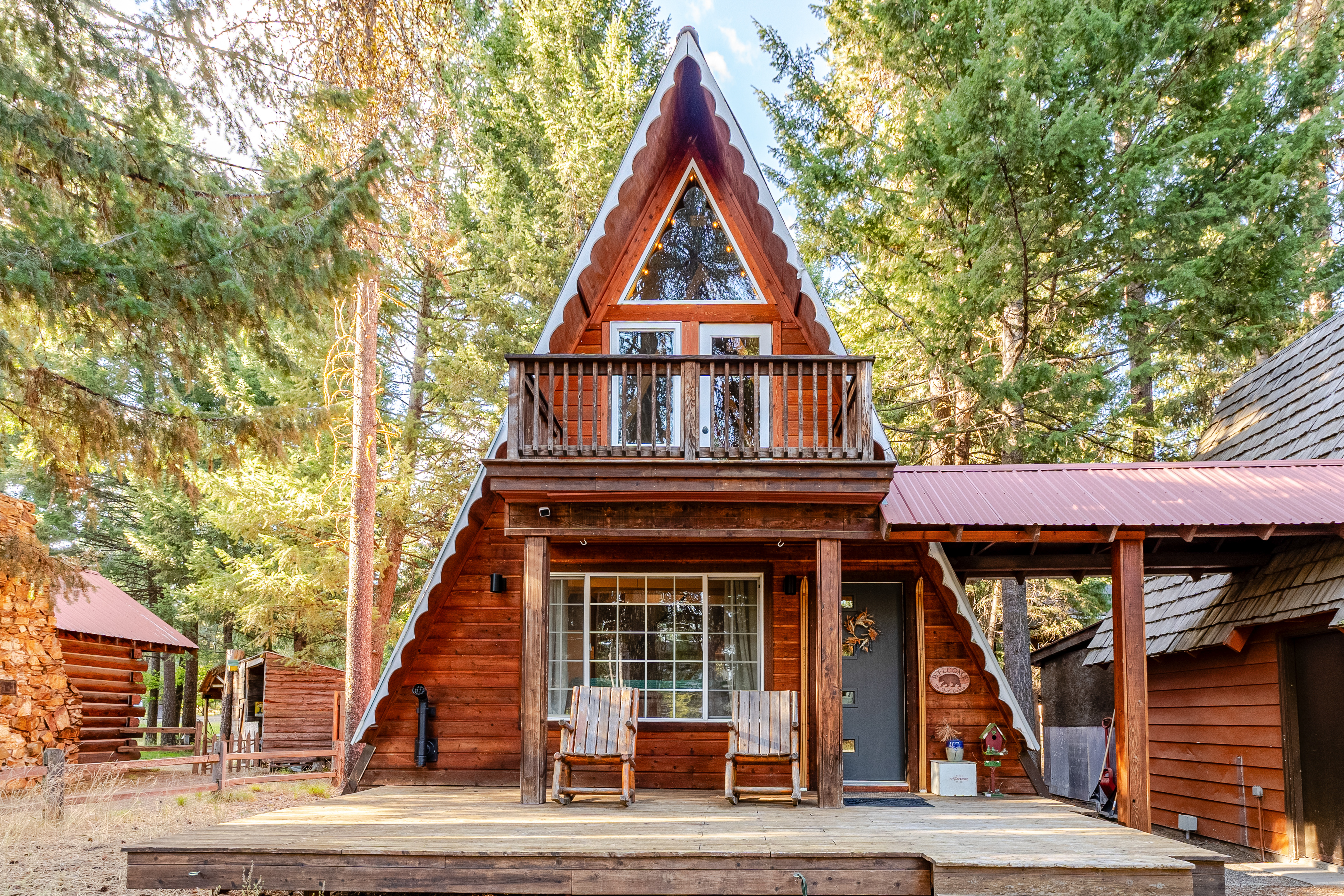 Wooden a-frame cabin surrounded by green trees.
