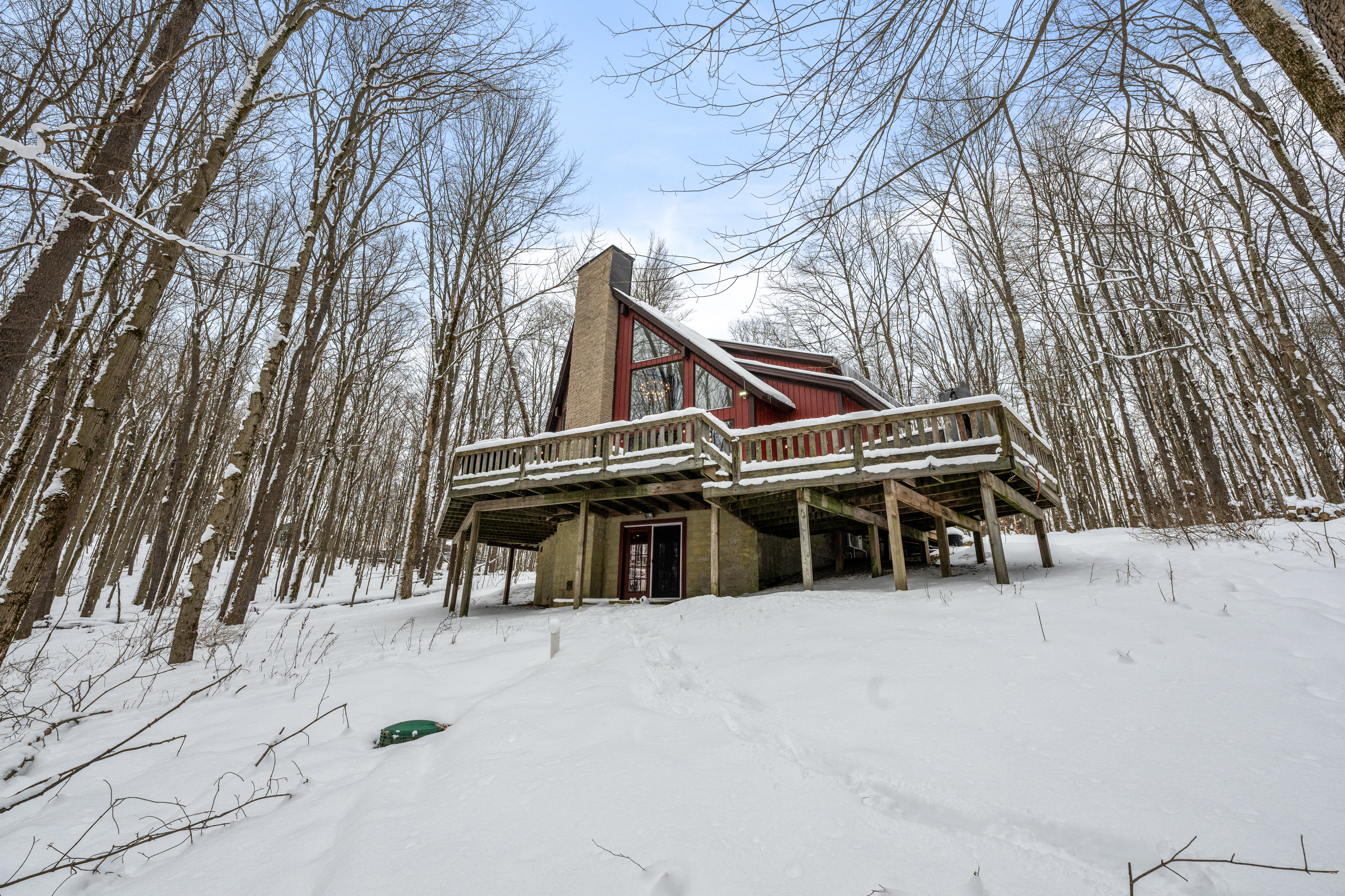 Large cabin covered in snow in the middle of the woods.