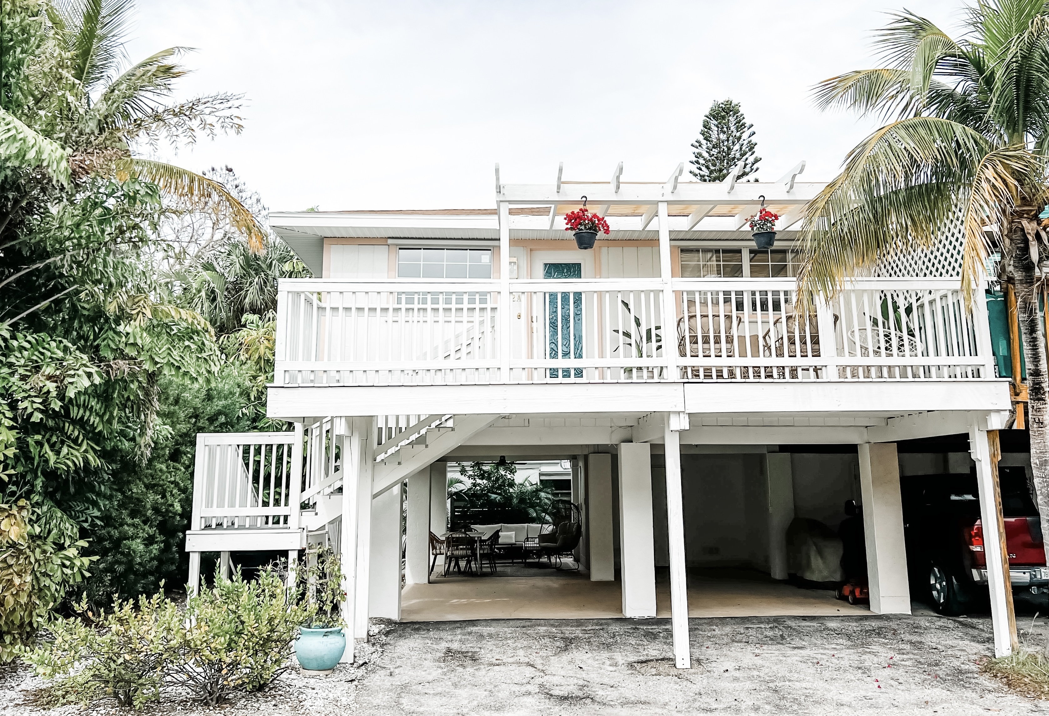 White villa with a front porch surrounded by palm trees.