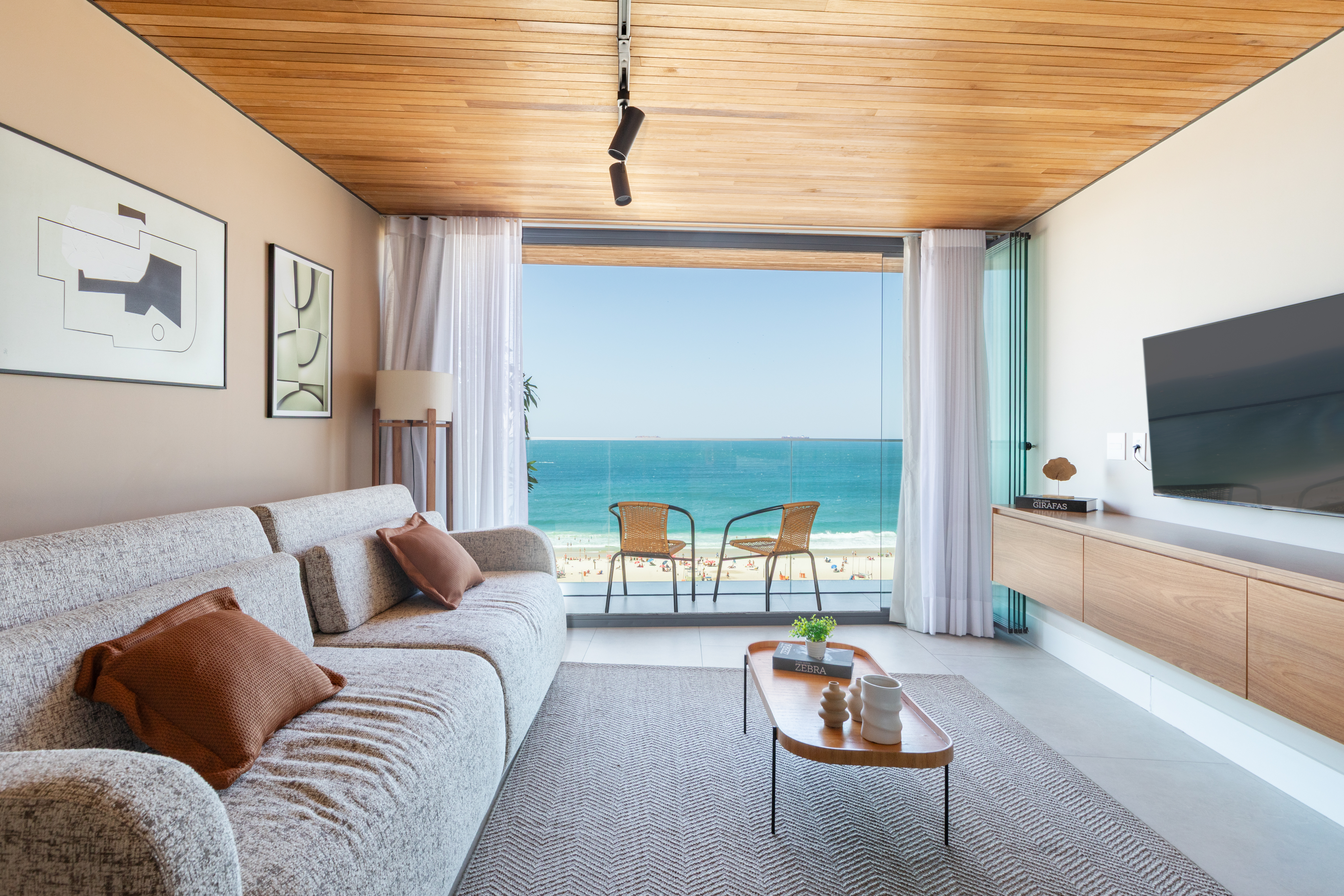 Contemporary living room with a panoramic glass wall offering stunning ocean views, minimalistic d&eacute;cor, and a cozy sofa.